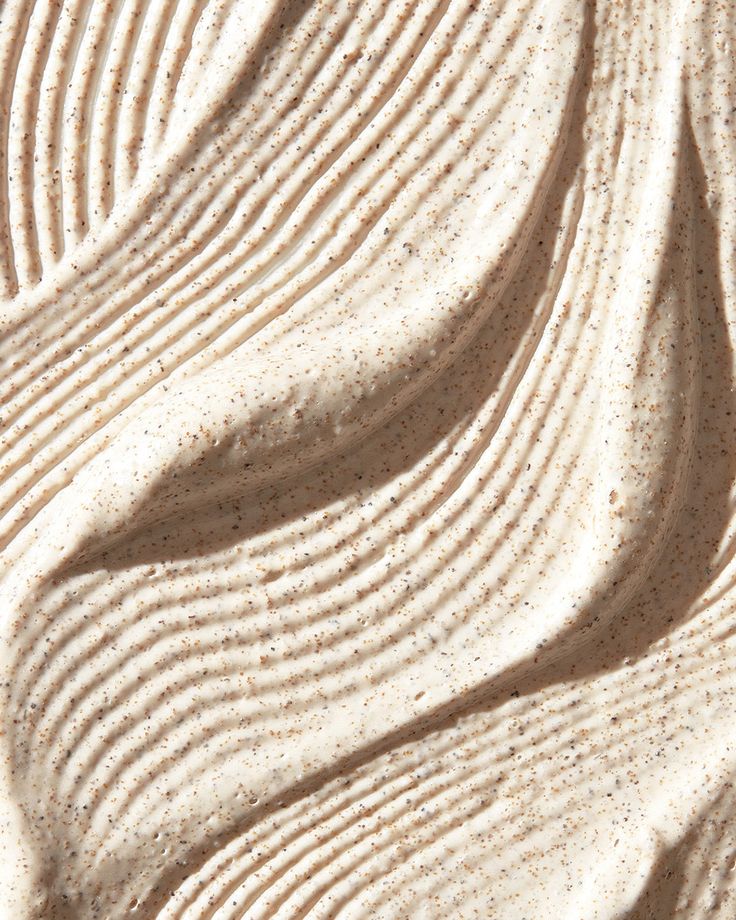 Textured cream with speckled particles and wavy patterns.