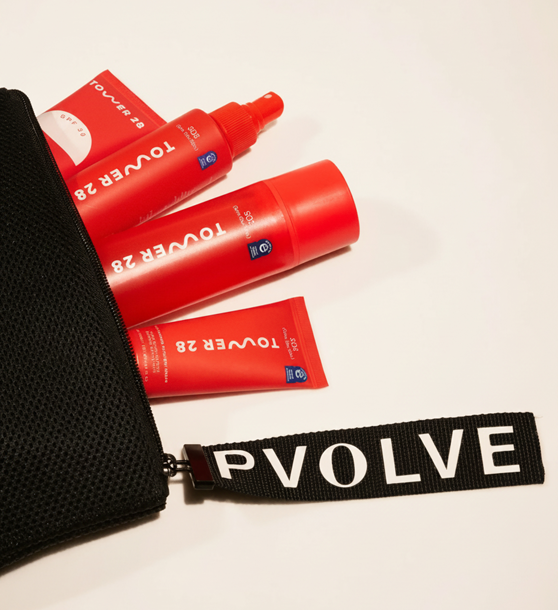 Red Tower 28 beauty products spilling out of a black Pvolve mesh bag onto a white surface.