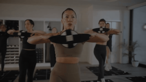 Group of people exercising with circular equipment in a fitness studio.
