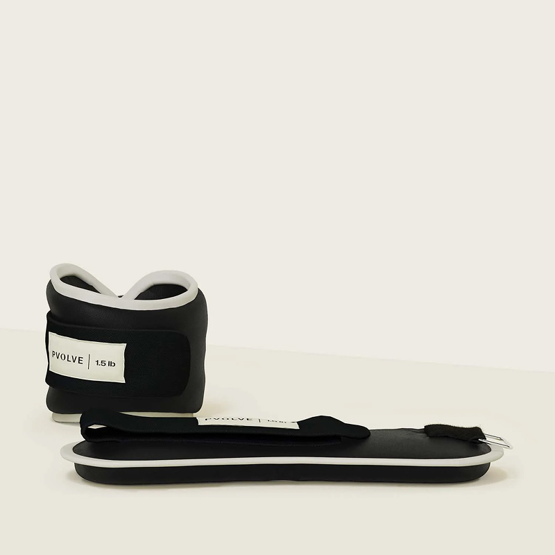 A pair of black and white Pvolve 1.5 lb ankle weights against a plain, off-white background.