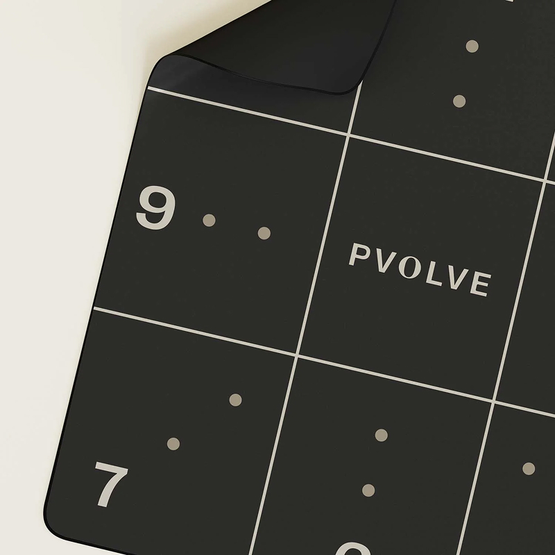 A close-up of a black Pvolve exercise mat with a white grid, numbers, and dots.