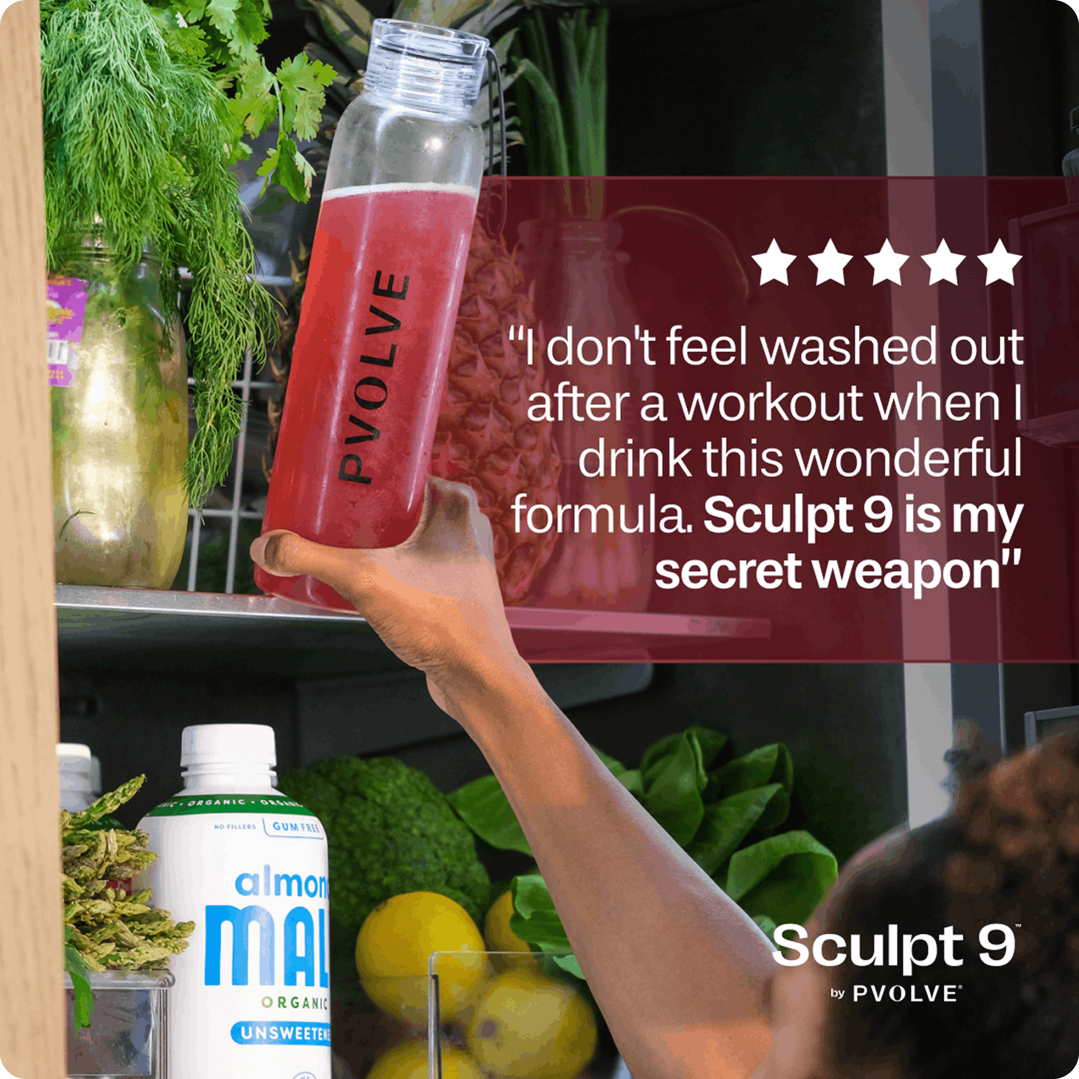 A hand takes a Pvolve bottle with red liquid out of a refrigerator full of produce.