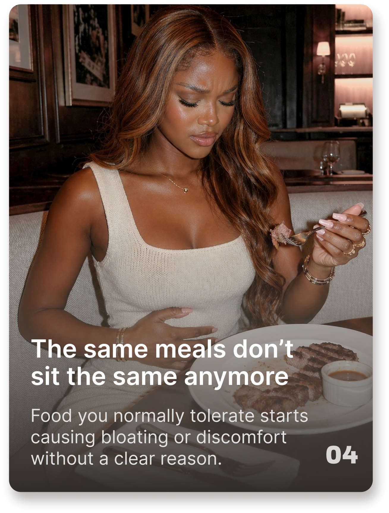 A woman holds her stomach in discomfort while eating a meal at a restaurant.