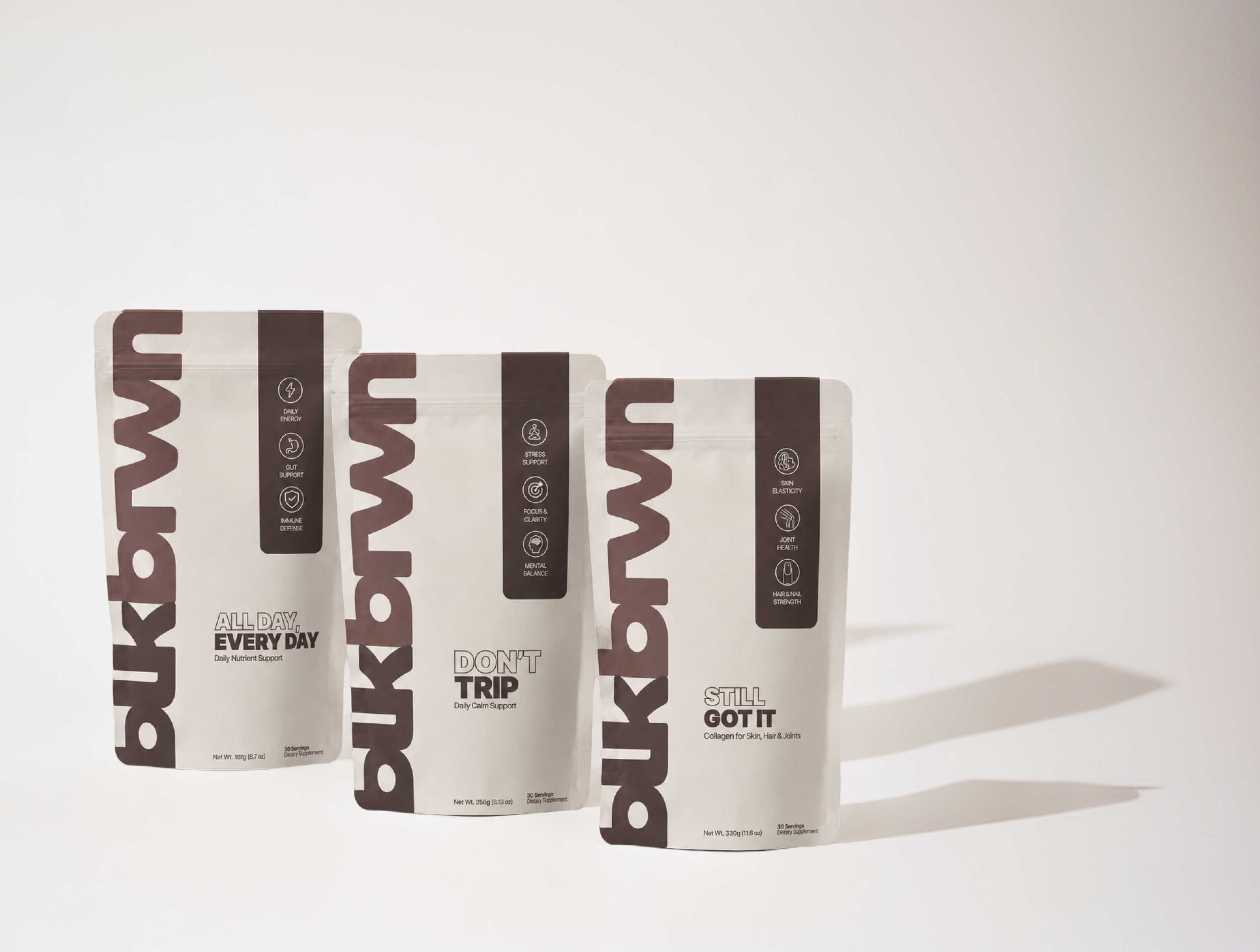 Three white and brown pouches of blkbrwn brand supplements arranged against a plain, off-white background.