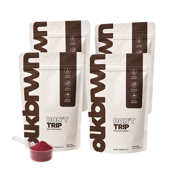 Four pouches of 'Don't Trip' daily calm support with a scoop of red powder in the foreground.