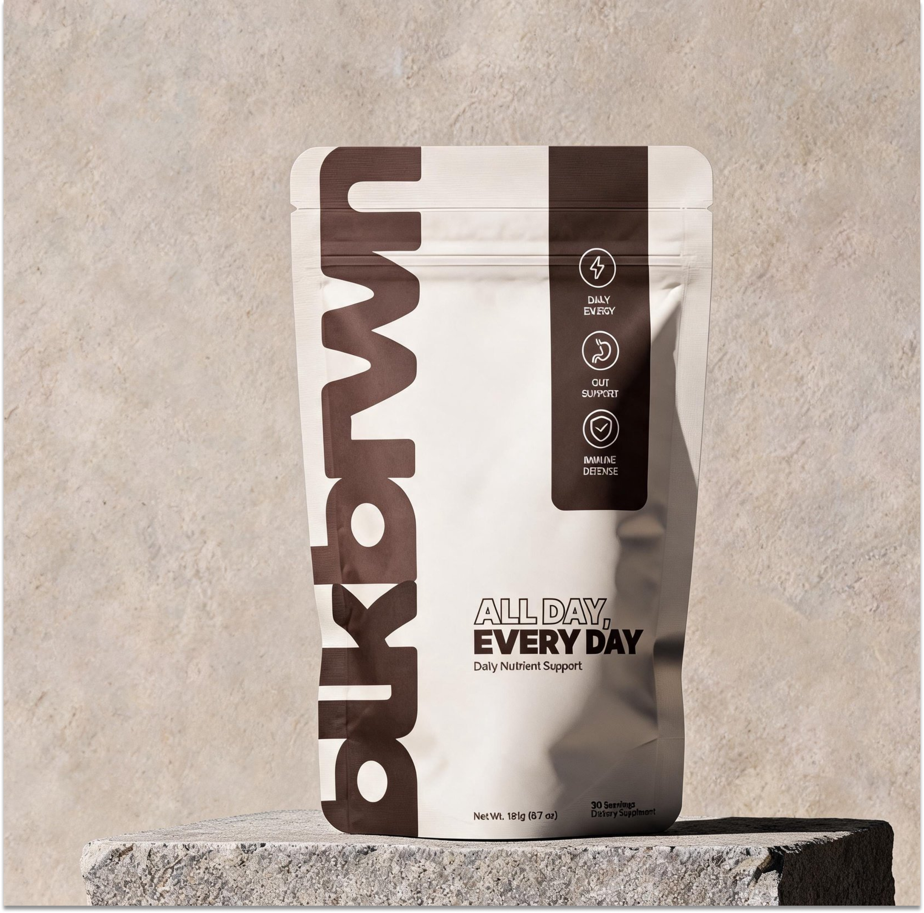 A white and brown pouch of Bkdwn All Day, Every Day daily nutrient support on a stone block.
