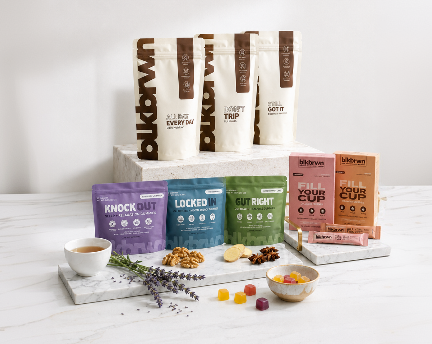 An assortment of blkbrwn wellness gummies and powders are artfully arranged on marble slabs with various ingredients.