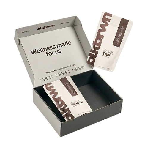 An open blkbrwn box with two wellness product pouches on a white background.