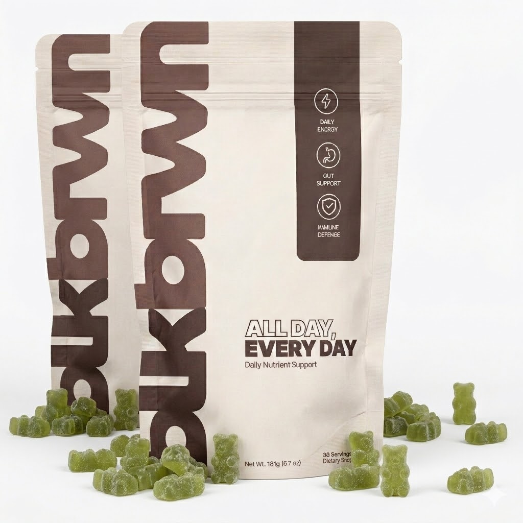 Two pouches of ukbrwn All Day, Every Day daily nutrient support, with green gummy bears scattered in front.