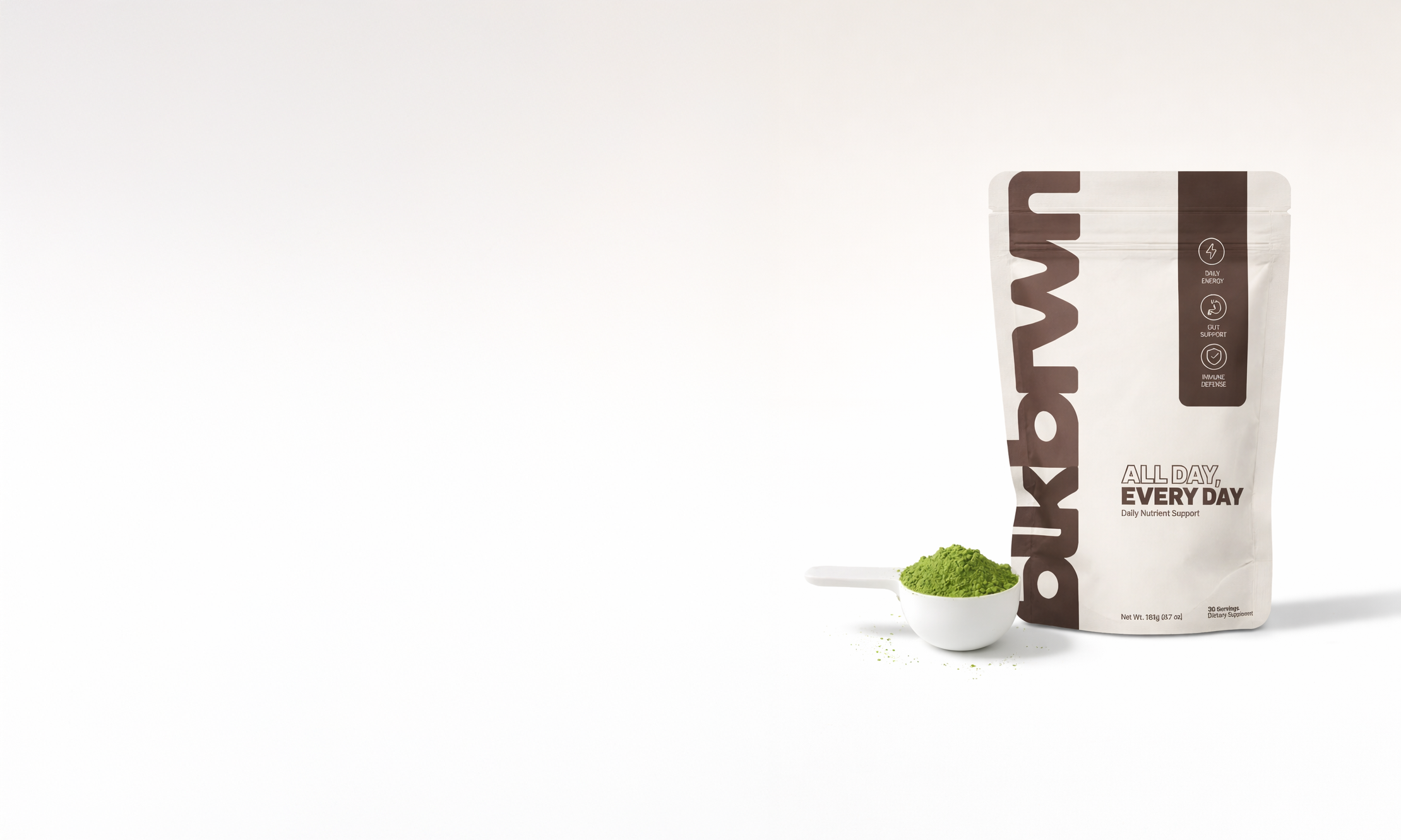 A pouch of blkbrwn All Day, Every Day nutrient support with a scoop of green powder.