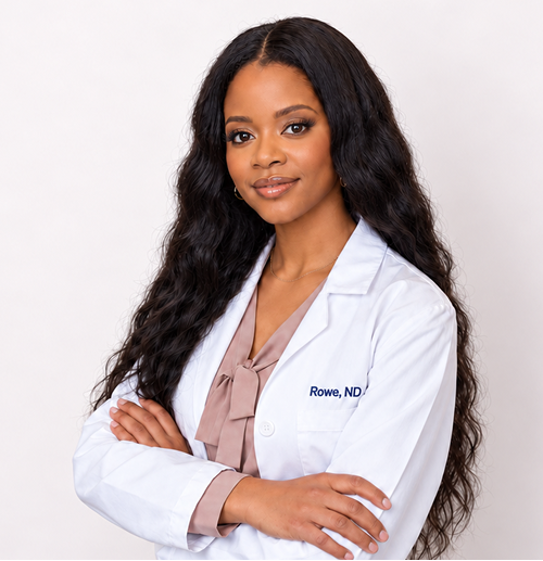 A woman with long wavy hair wearing a white lab coat with her arms crossed and smiling slightly.
