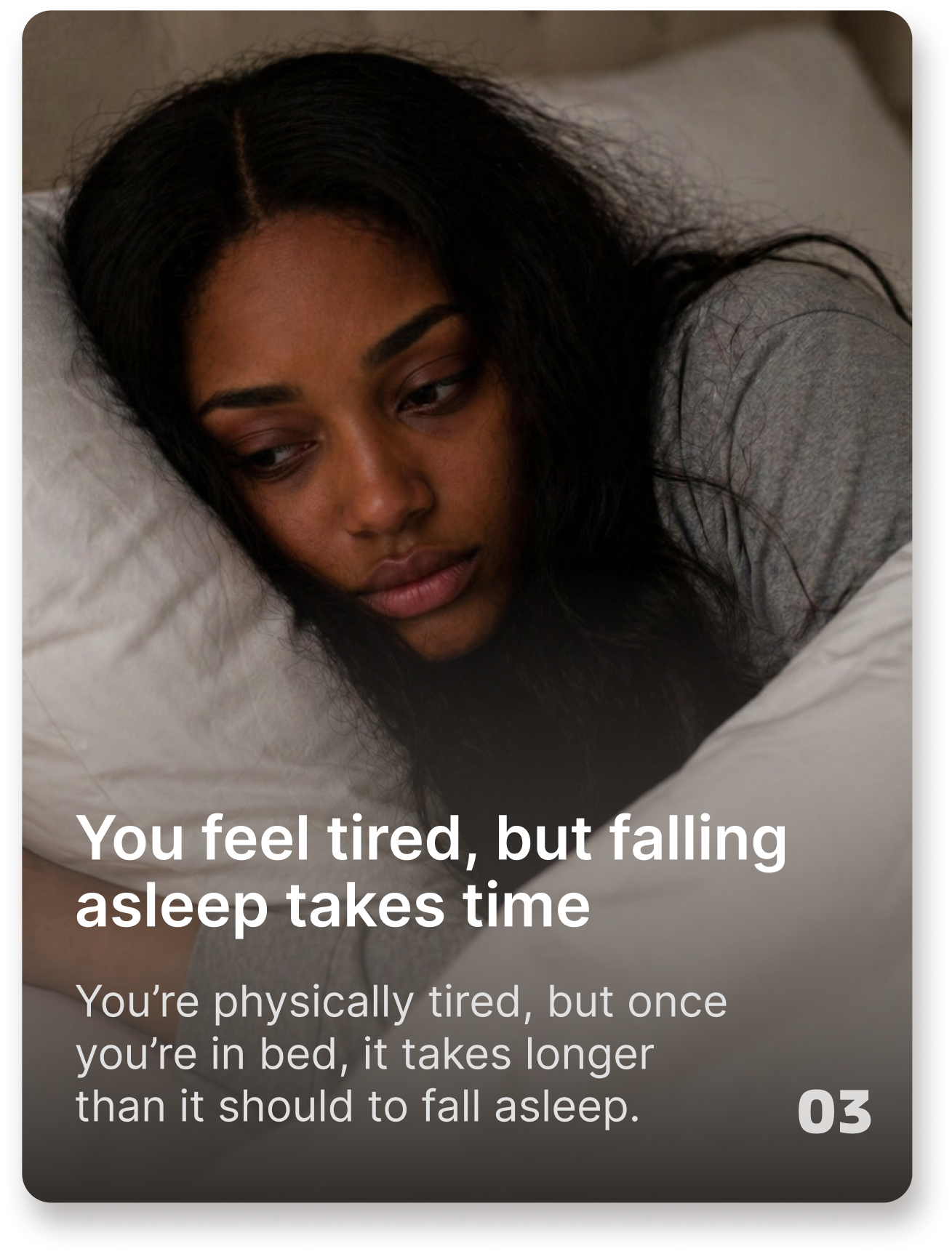A woman with a somber expression lies in bed, resting her head on a white pillow.