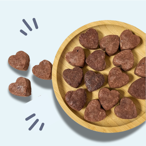Heart-shaped cookies on a wooden plate with some cookies outside the plate.
