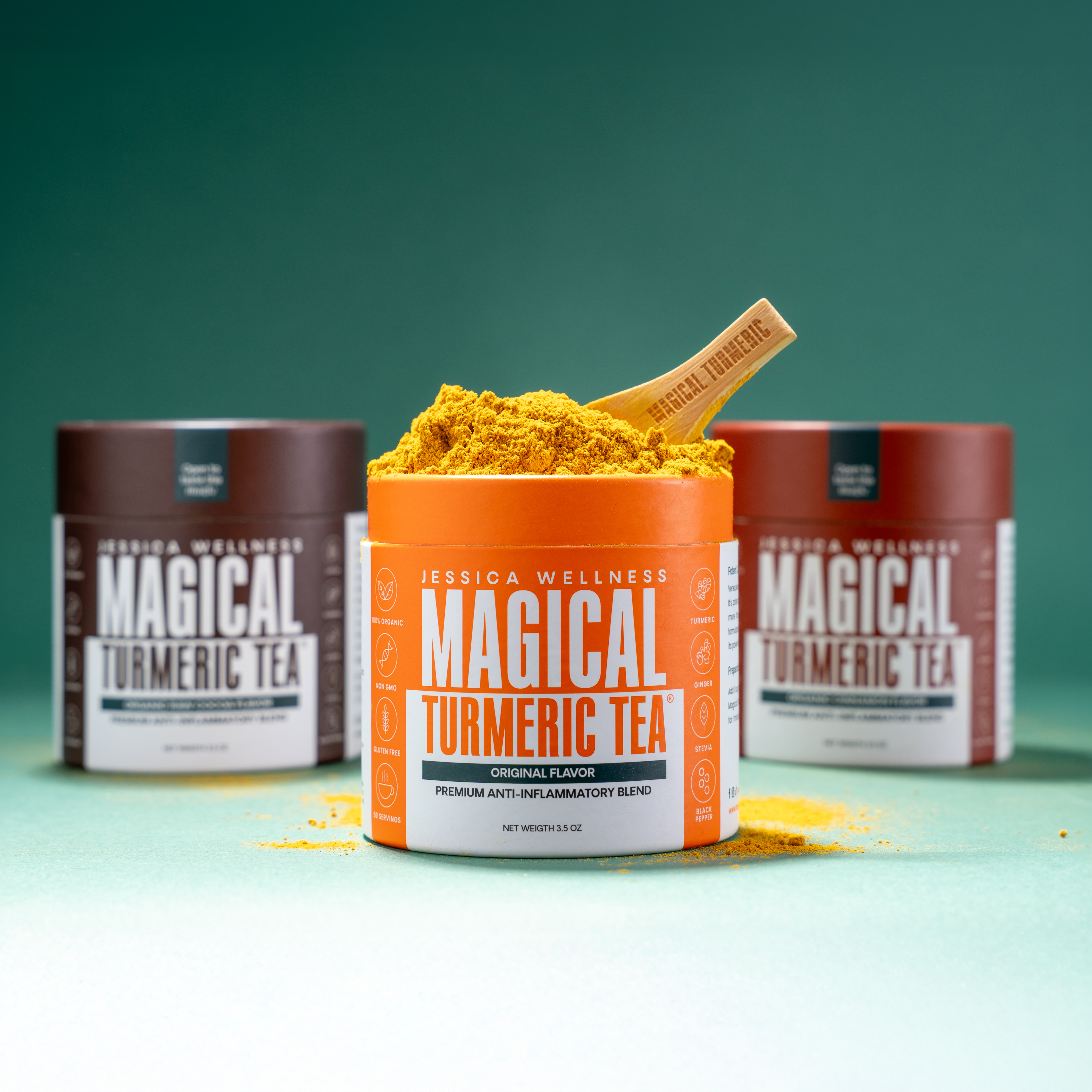 An open jar of Magical Turmeric Tea powder with a scoop, with two other jars in the background.