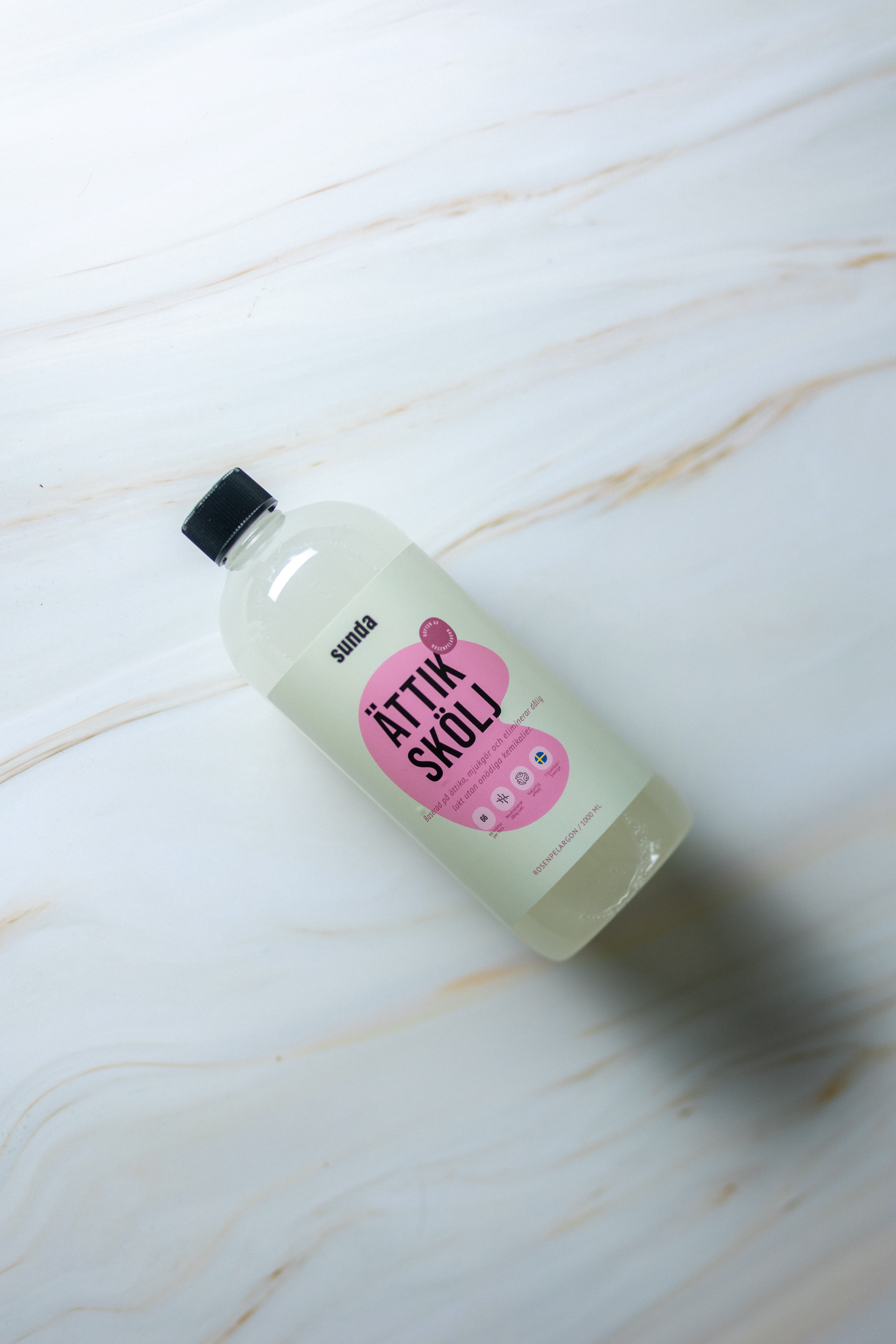 Clear bottle with a black cap on a marble surface.