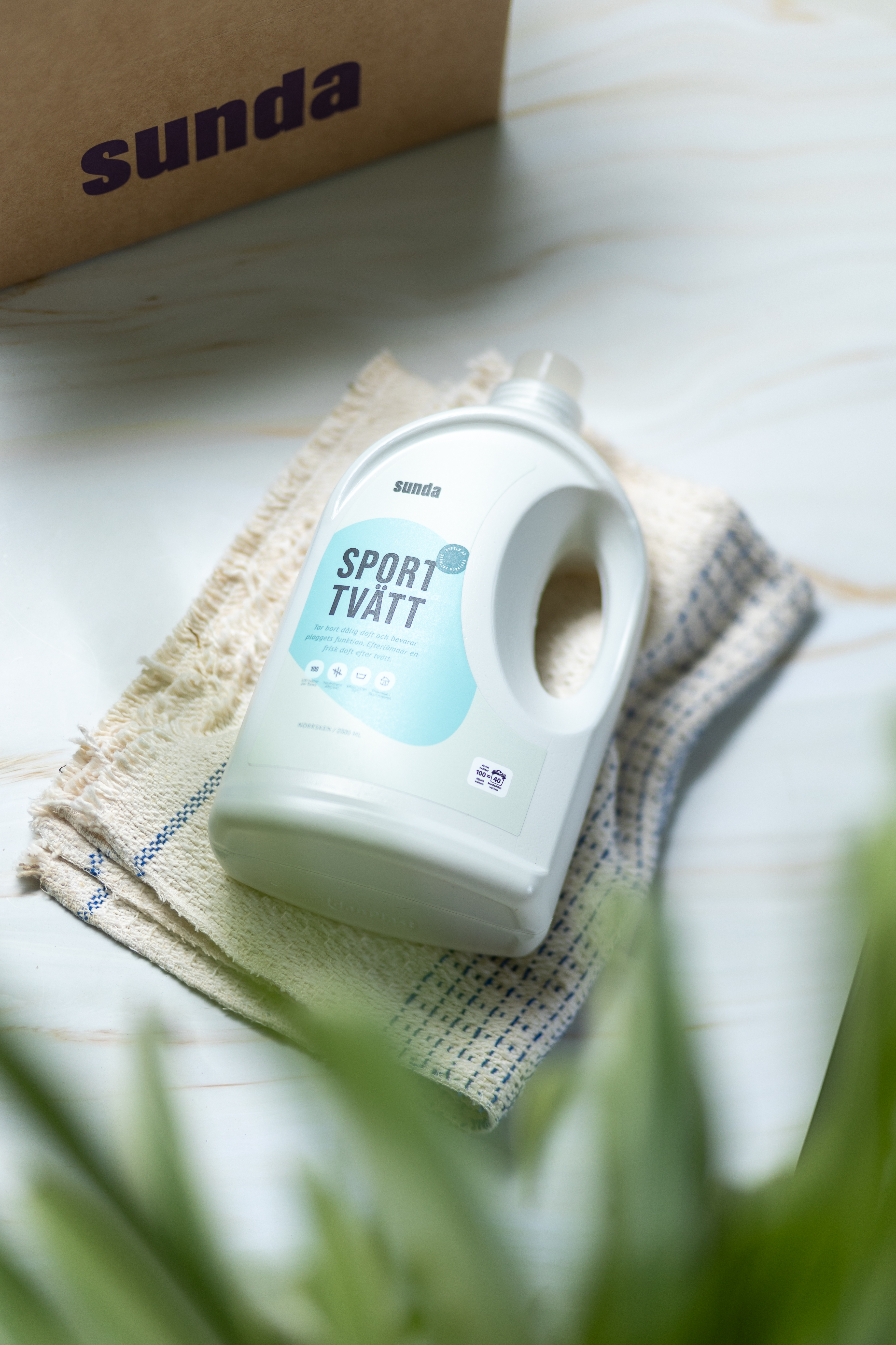 Laundry detergent bottle on a cloth, with a cardboard box in the background.
