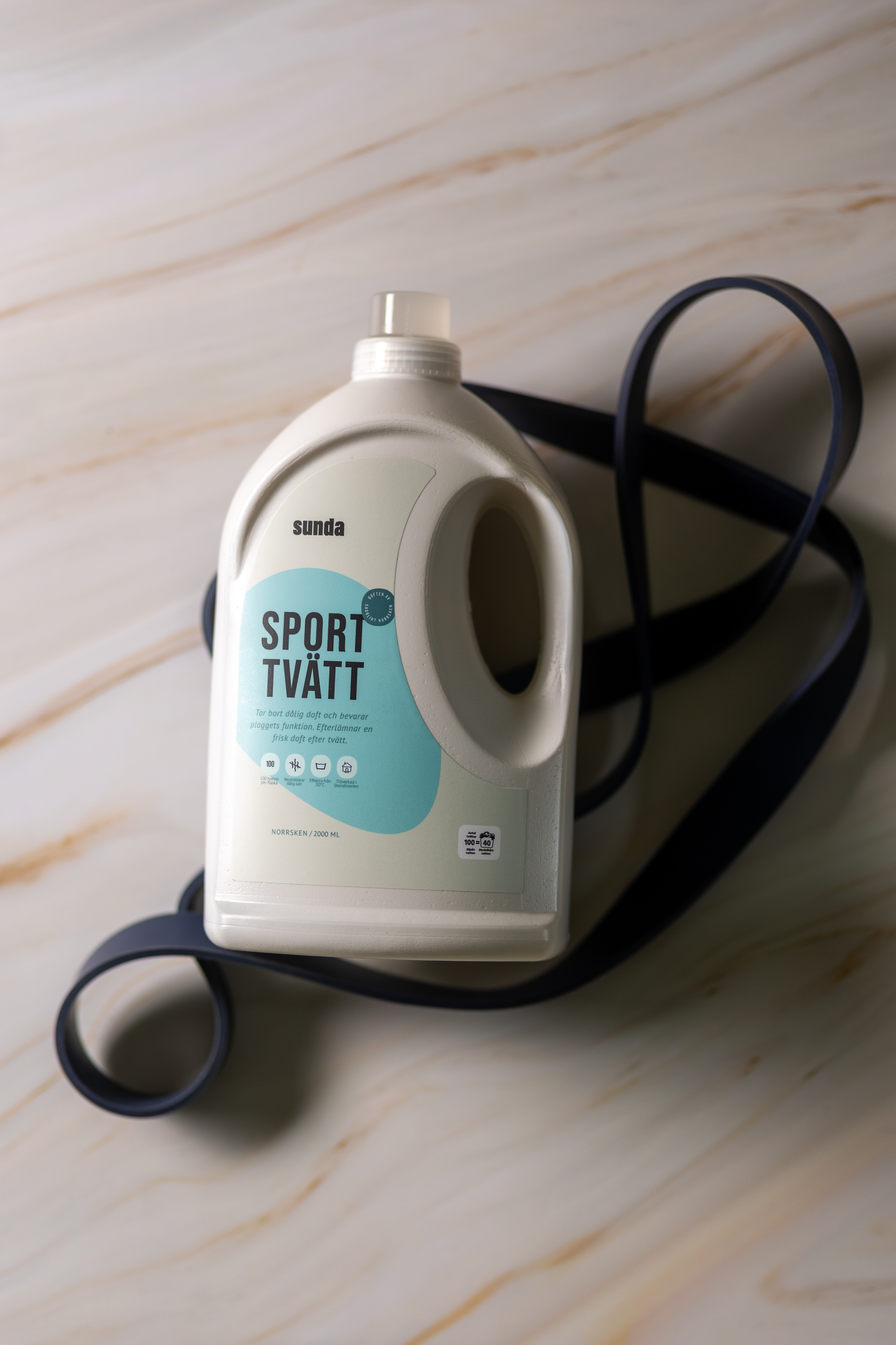 A bottle of laundry detergent labeled 'Sport Tvätt' on a marble surface.