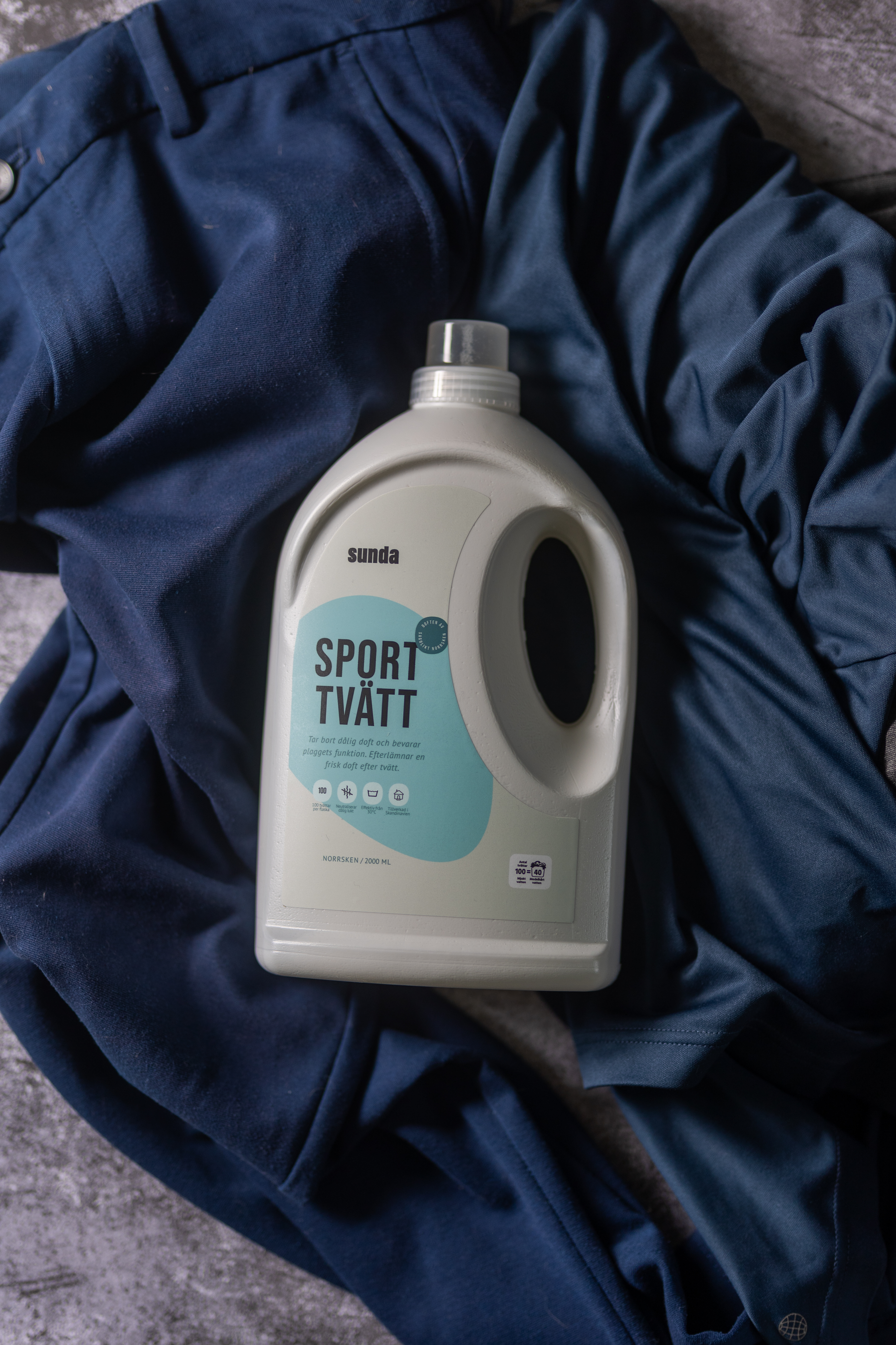 Laundry detergent bottle on a dark blue fabric background.
