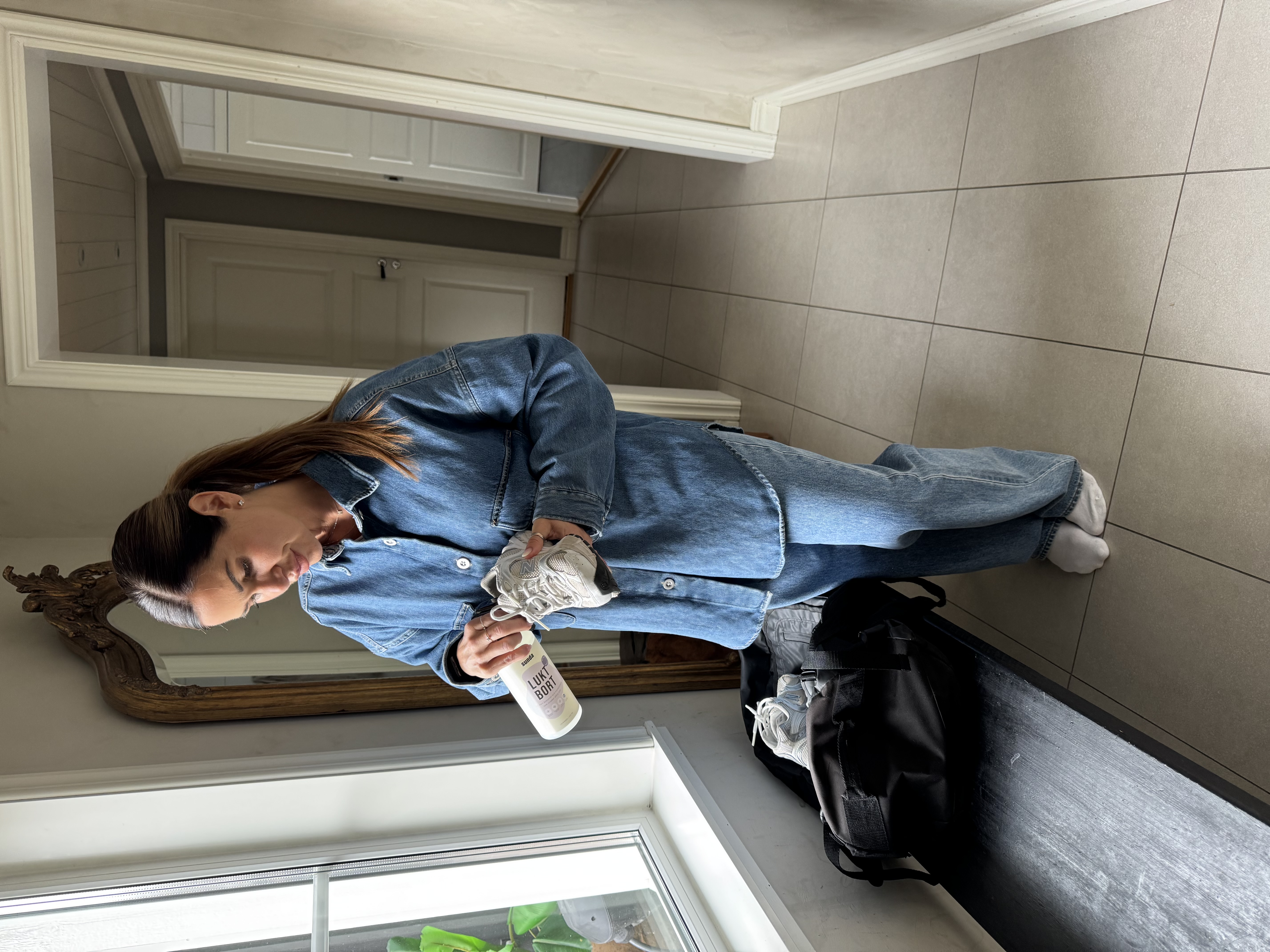 Person cleaning a sneaker with a spray bottle indoors.