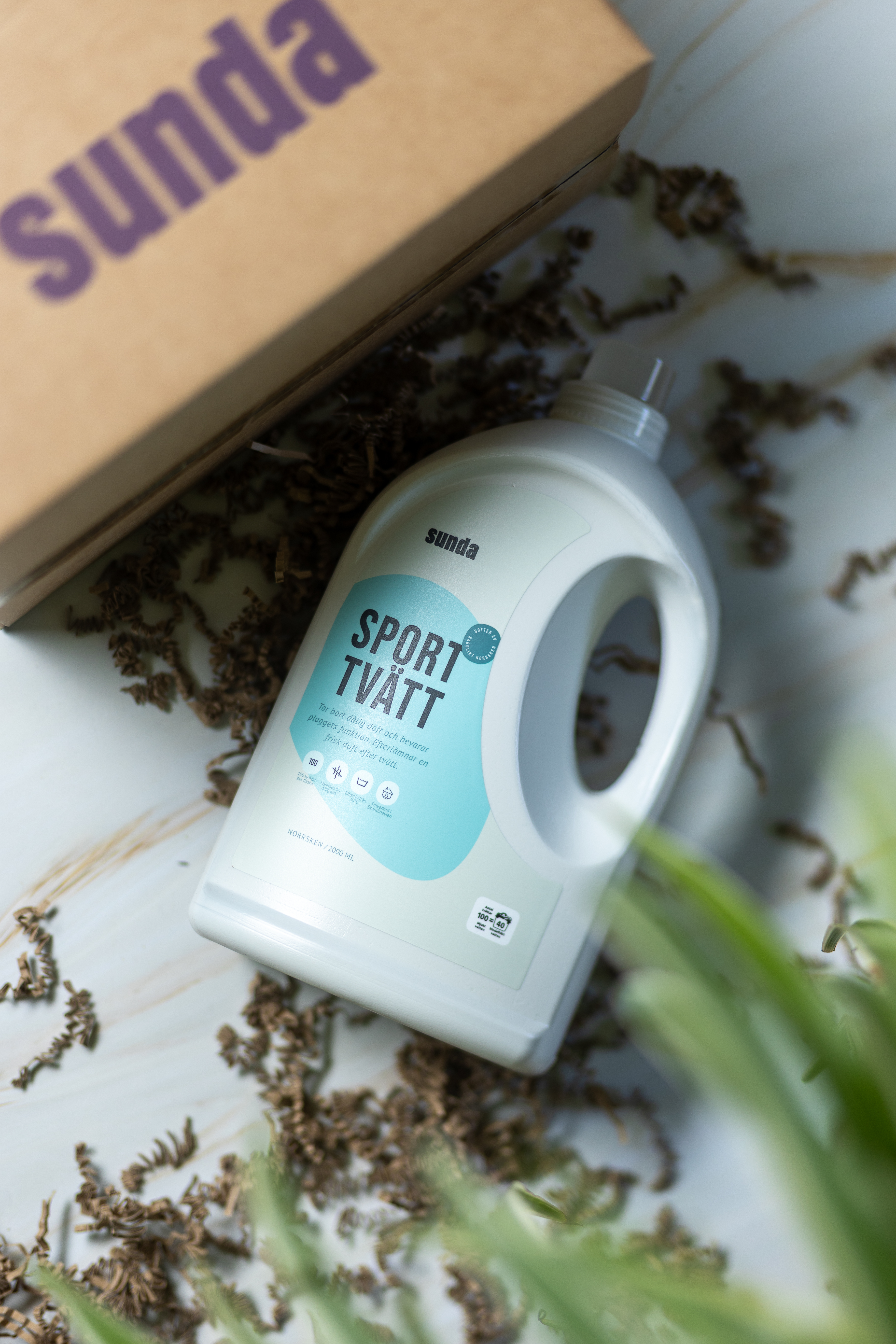 Laundry detergent bottle labeled 'Sport Tvätt' on a marble surface with a cardboard box.