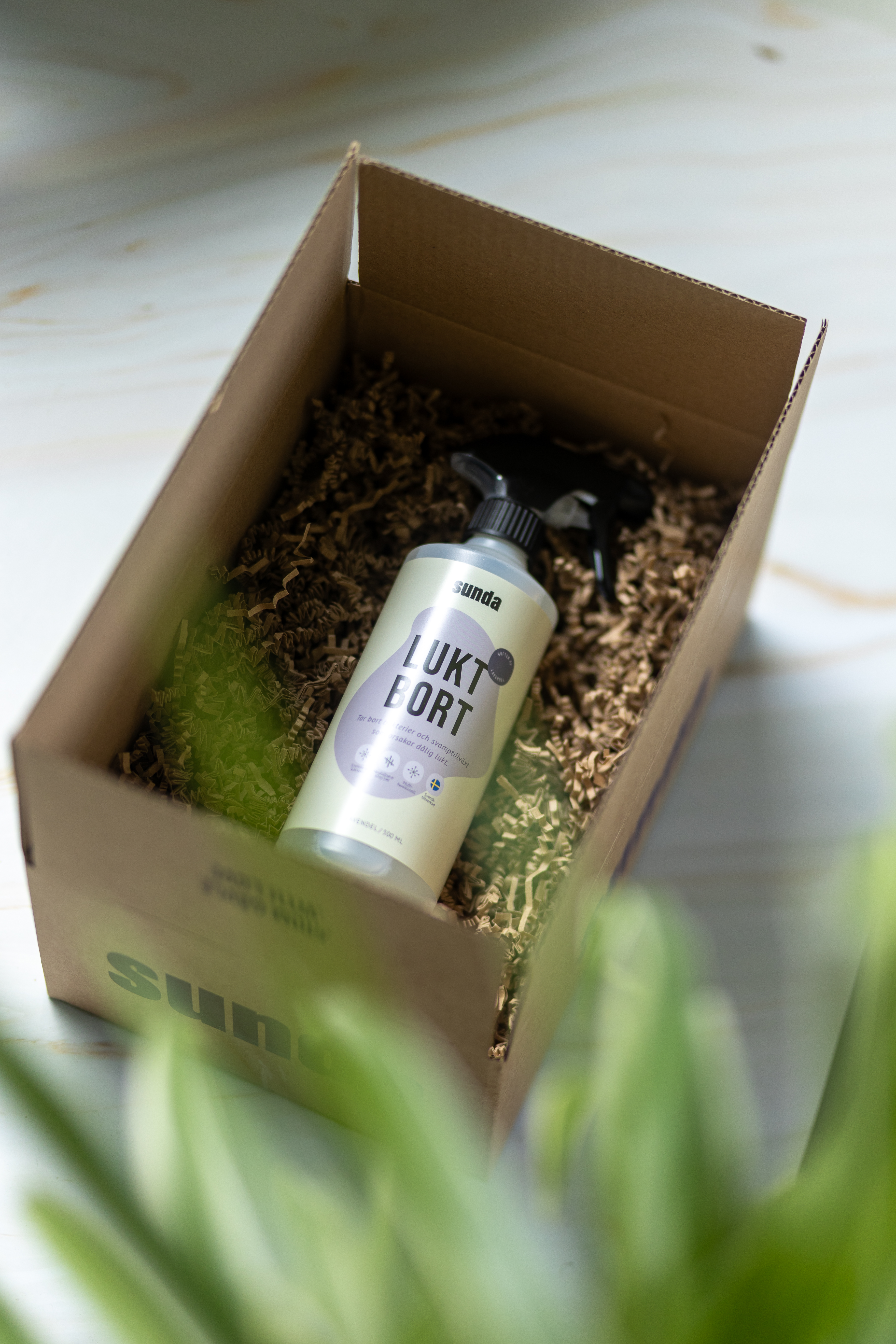 Spray bottle in a cardboard box with shredded paper packaging.