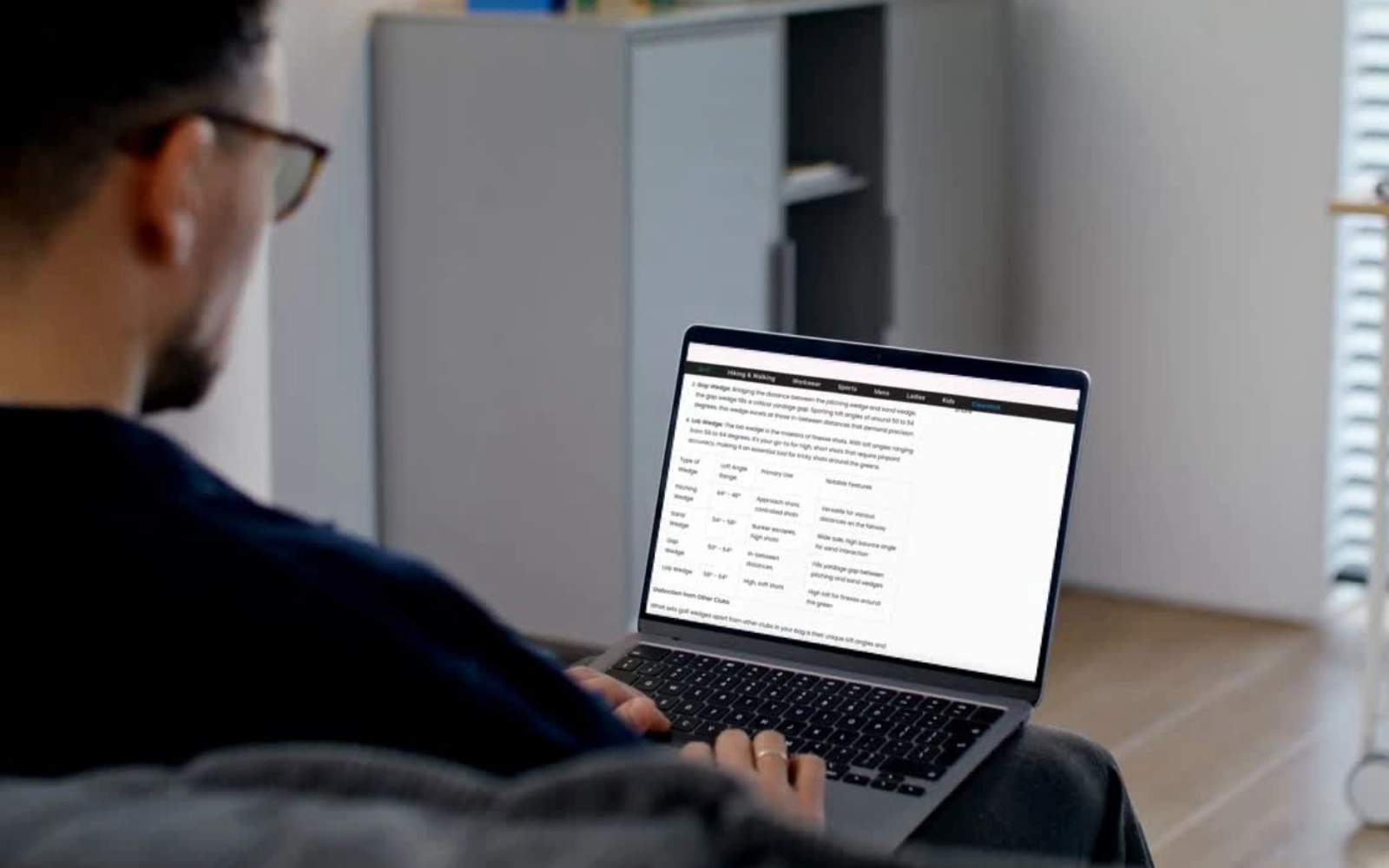 Person seated, using a laptop with text visible on the screen.