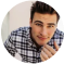 A person in a checkered shirt looking at the camera with a neutral expression.