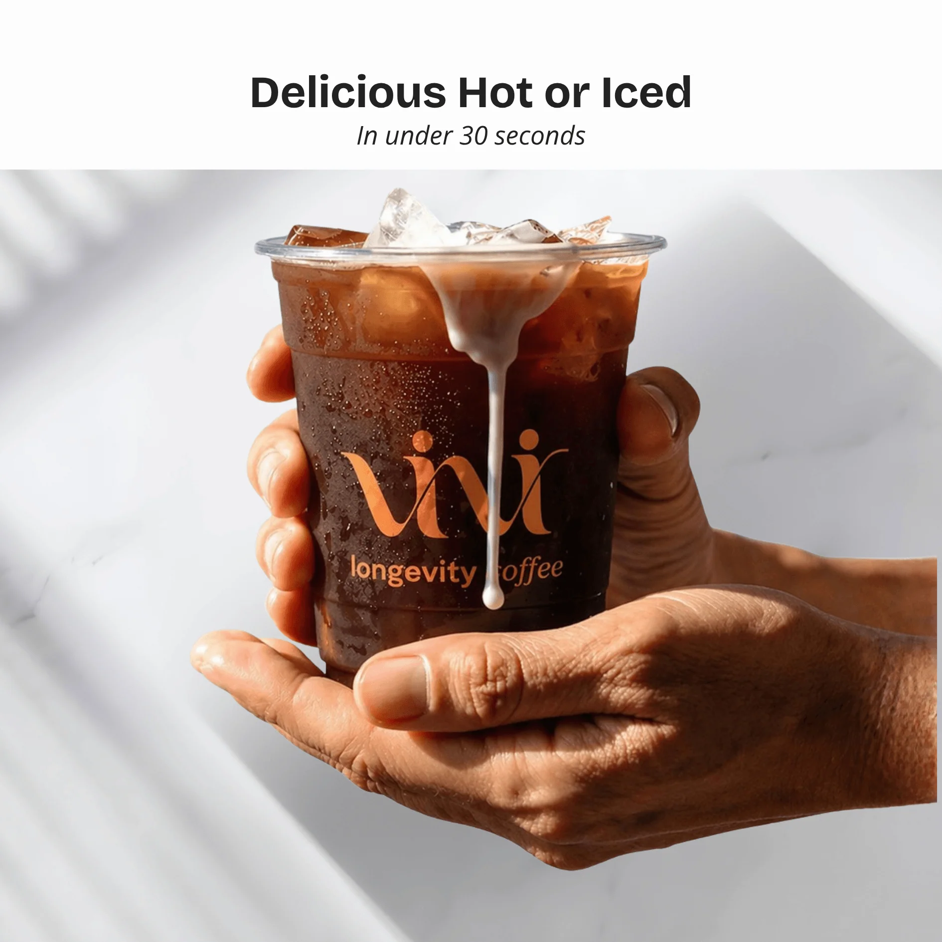 Hands holding a clear plastic cup of iced coffee with cream being poured in.