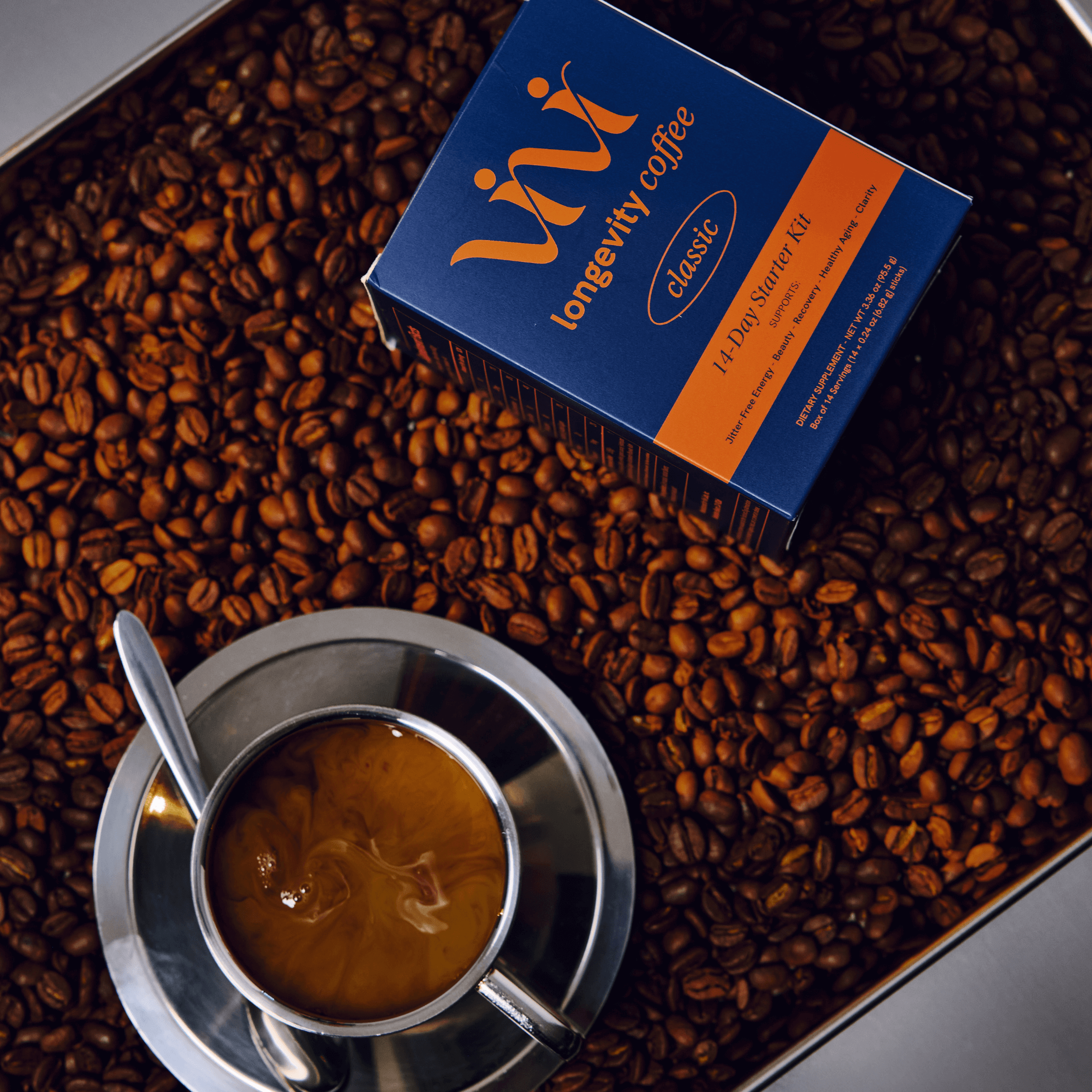 A box of longevity coffee and a cup of coffee sit in a tray of coffee beans.