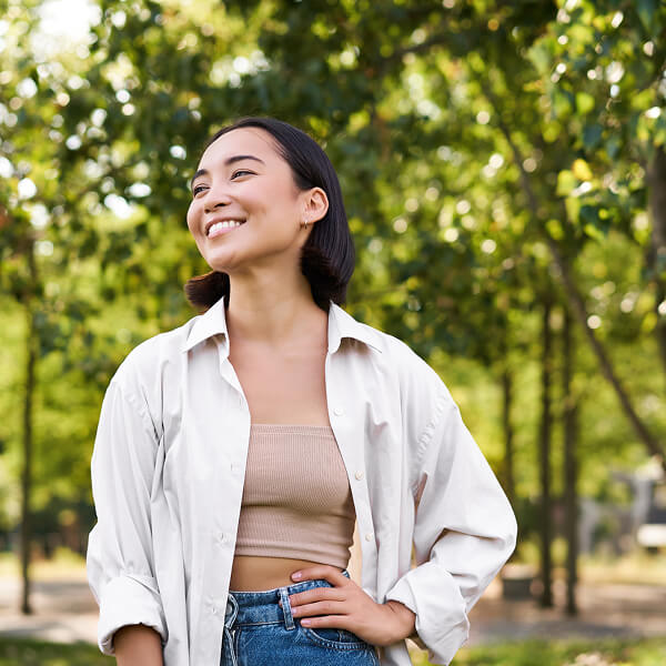 Smiling person standing outdoors with trees in the background.