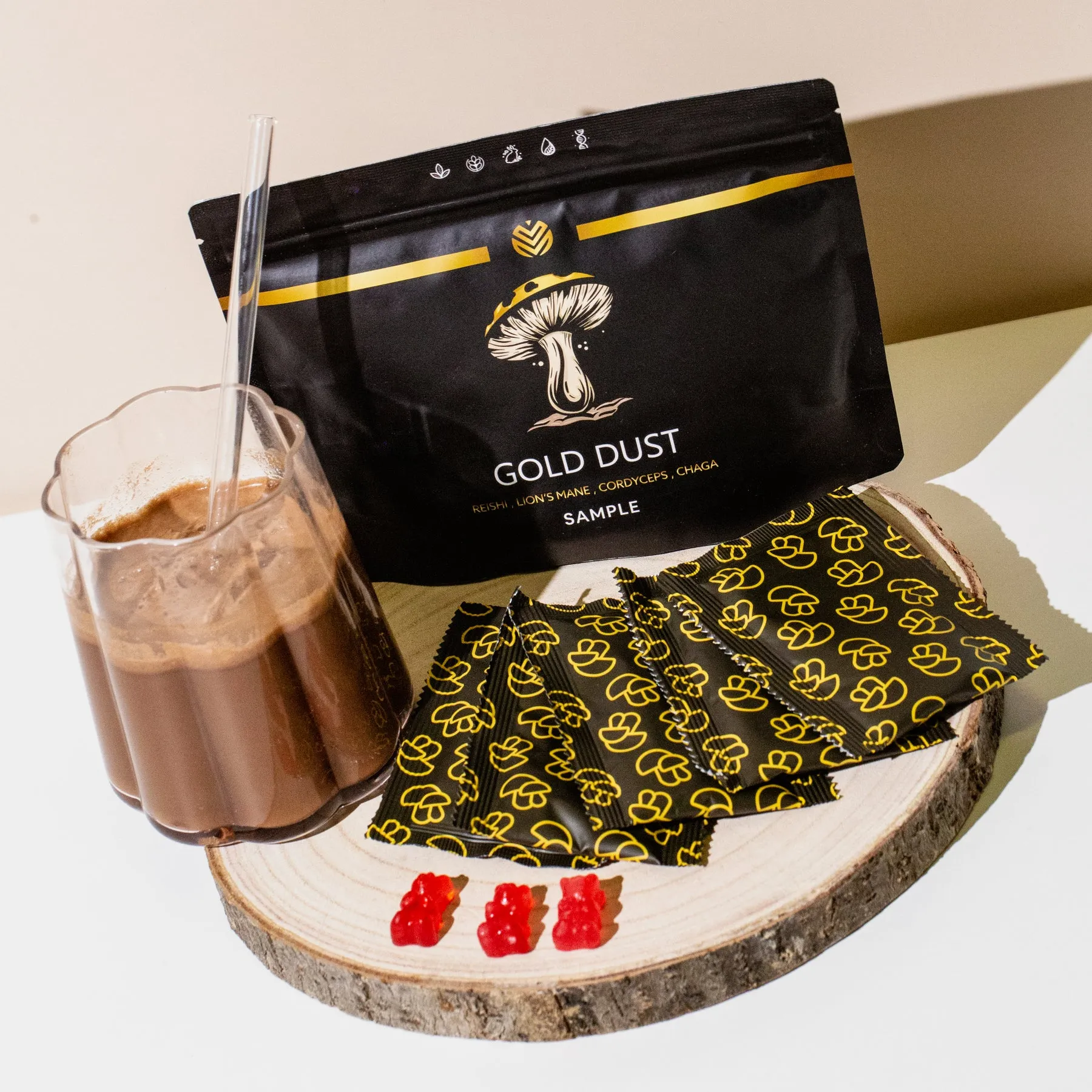 Gold Dust mushroom powder, sample packets, red gummies, and a chocolate drink on a wood slice.