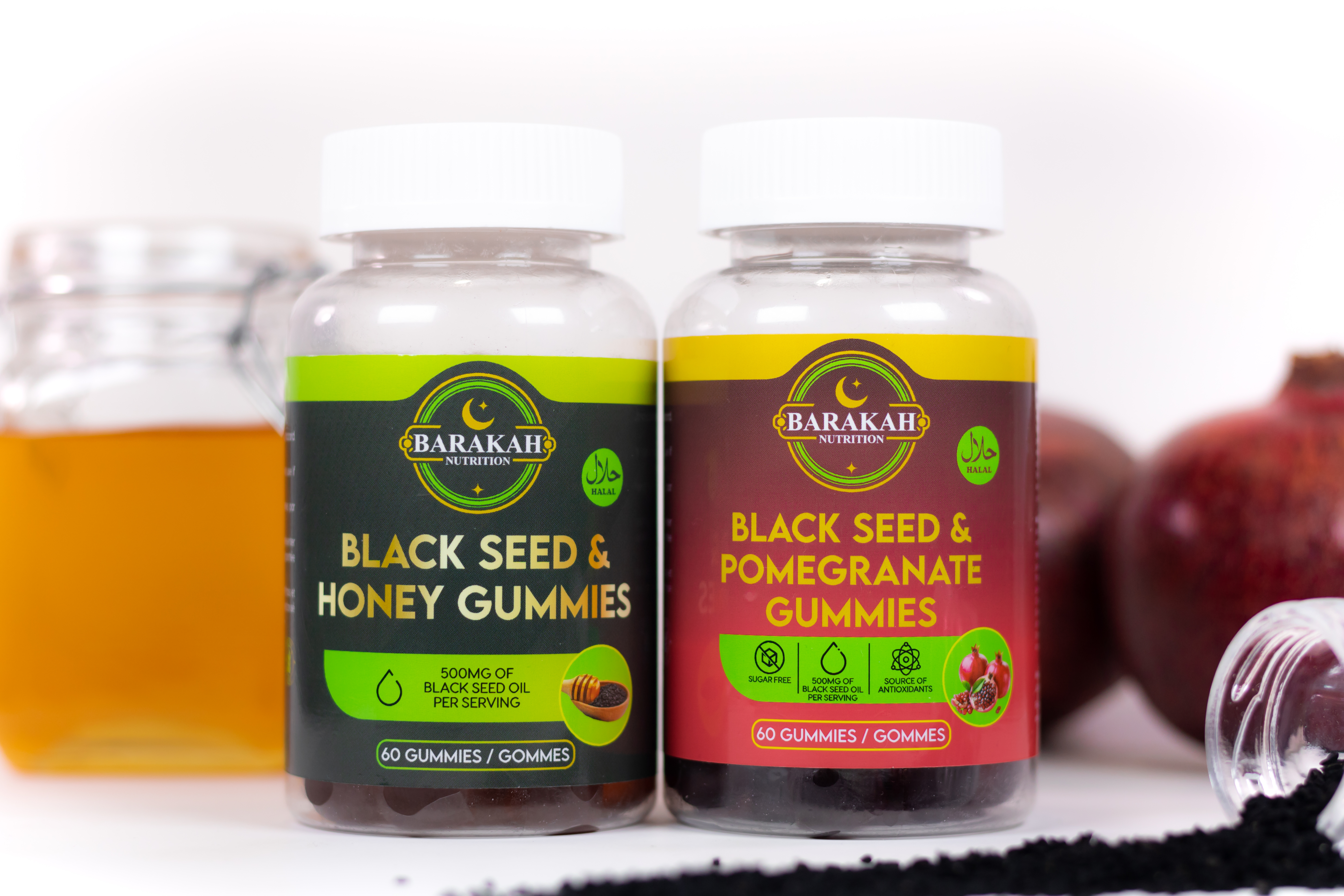 Two bottles of Barakah Nutrition gummies, Black Seed & Honey and Black Seed & Pomegranate, with surrounding ingredients.