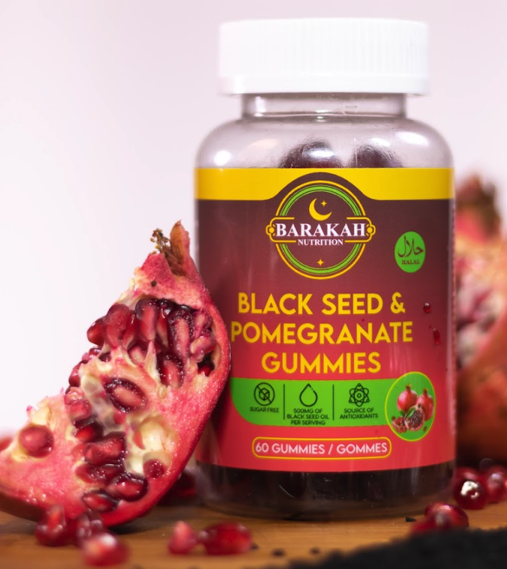 A bottle of Barakah Nutrition Black Seed & Pomegranate Gummies next to a slice of fresh pomegranate.