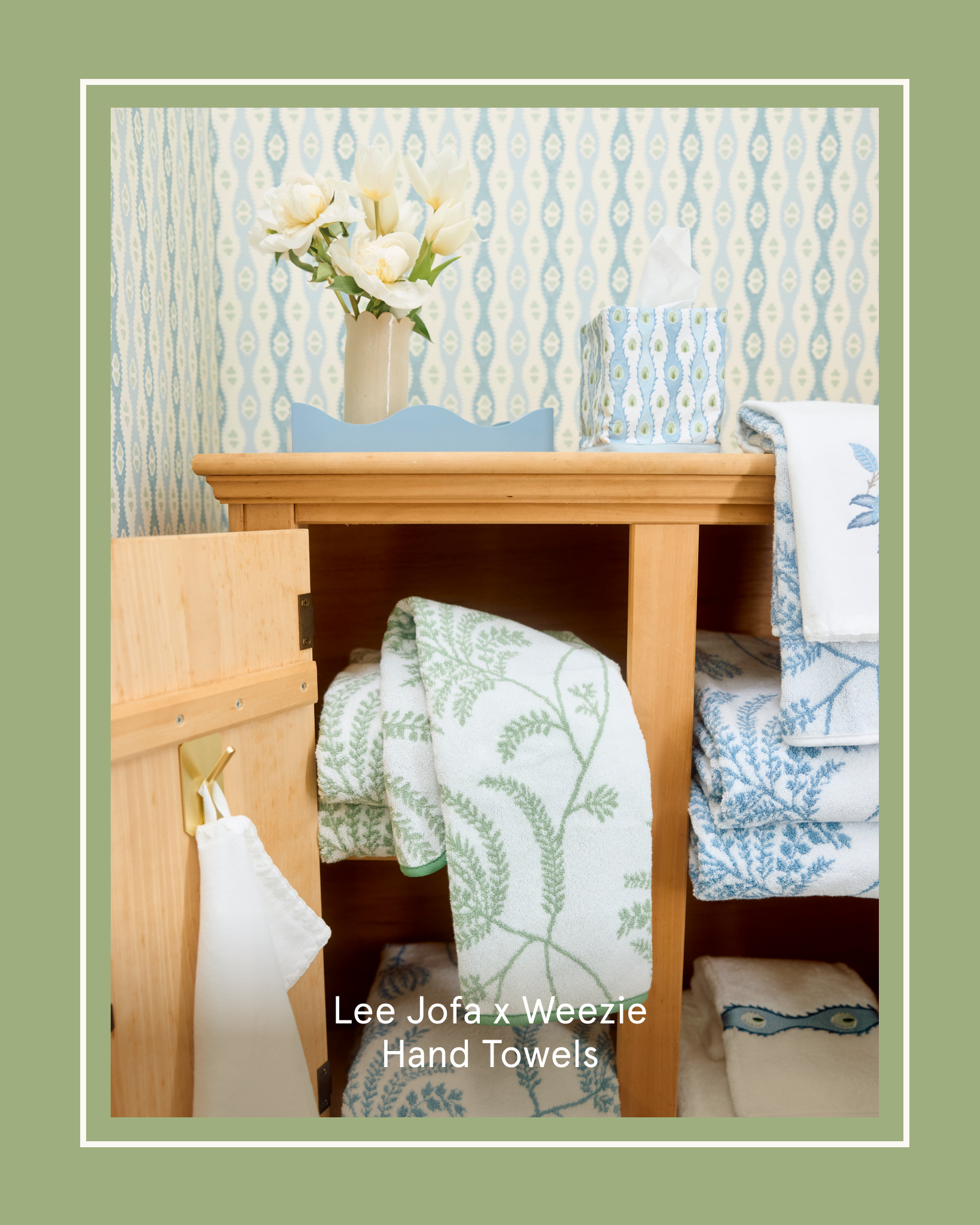 A wooden cabinet with its door open, filled with stacks of patterned green and blue hand towels.