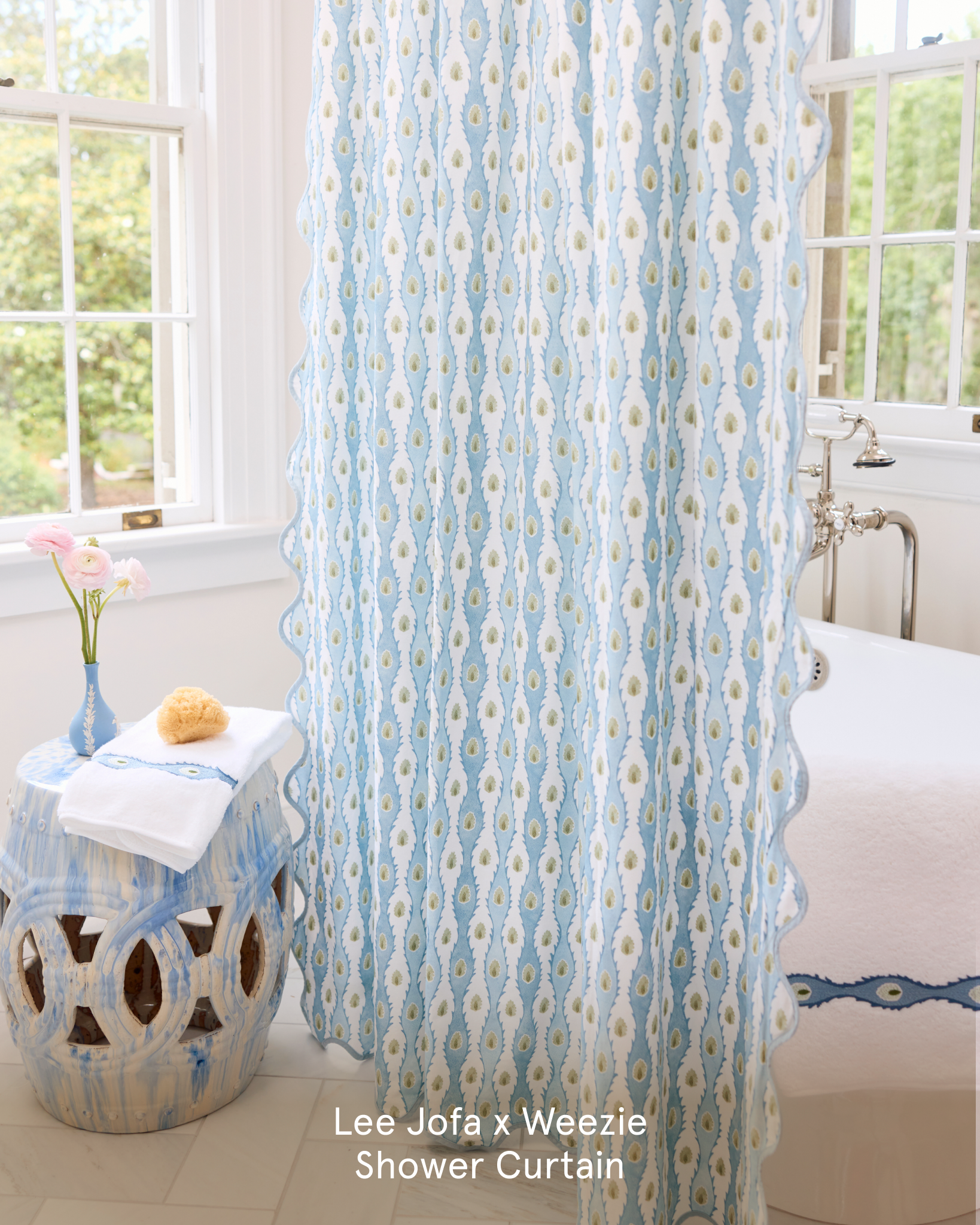 A blue and white patterned shower curtain with a scalloped edge next to a bathtub and ceramic stool.