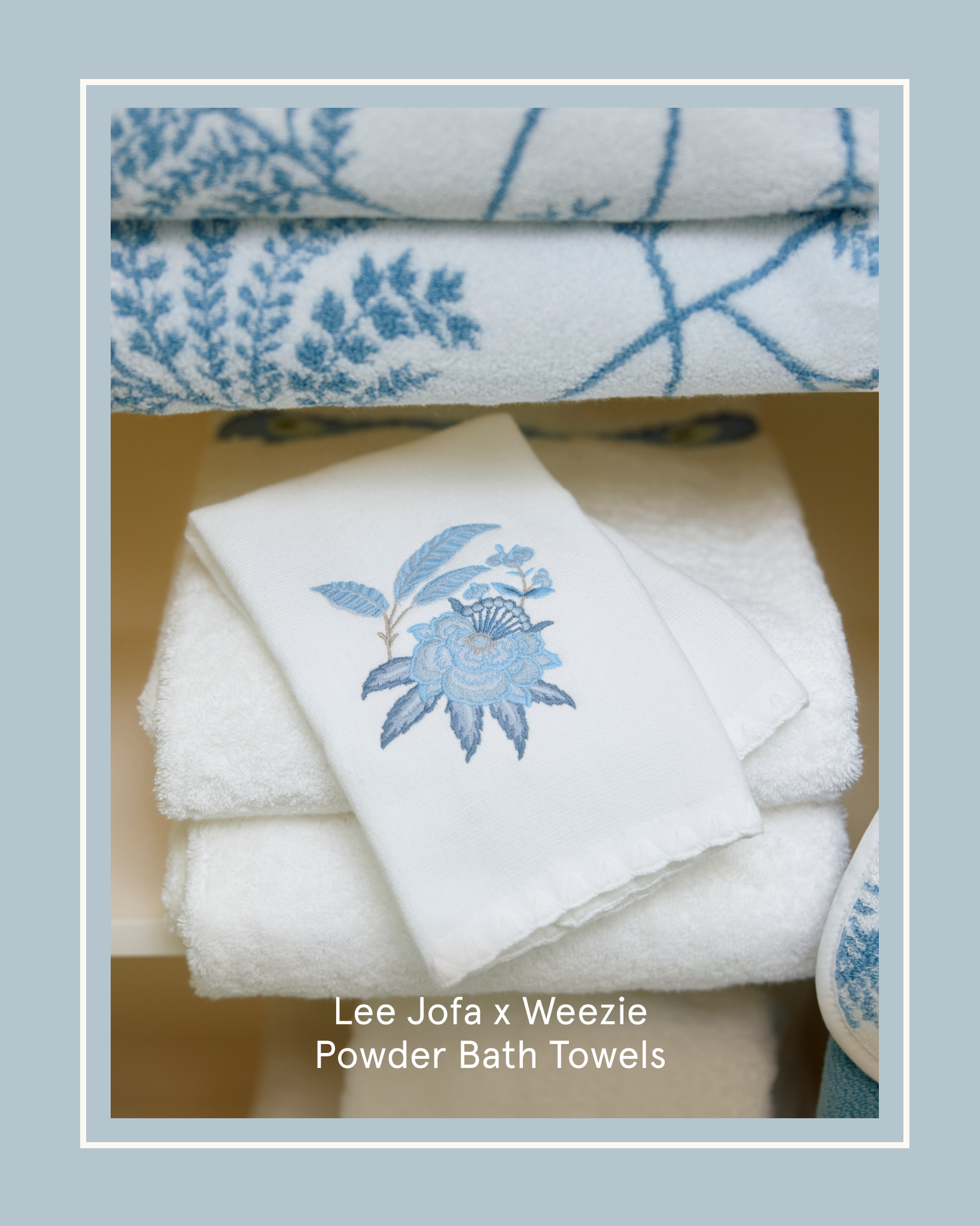 Stacked white towels with blue embroidered floral and vine patterns on a shelf.