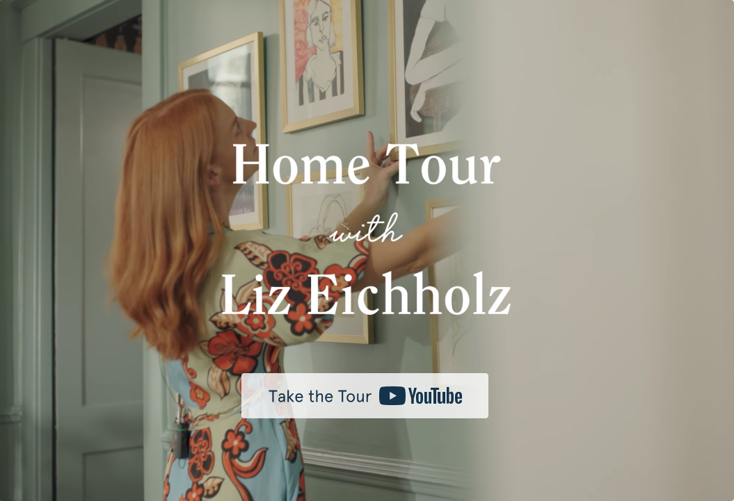 A woman with red hair adjusts a framed picture on a gallery wall for a home tour video.