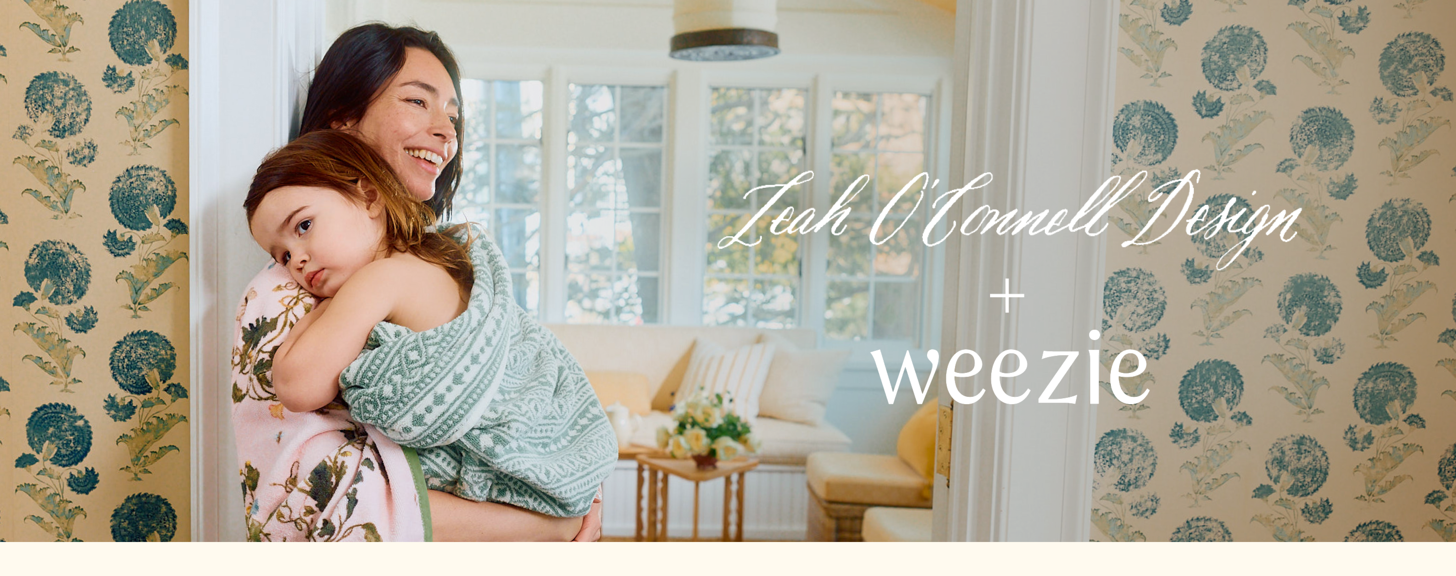 A smiling woman holds a young child who is wrapped in a patterned towel.
