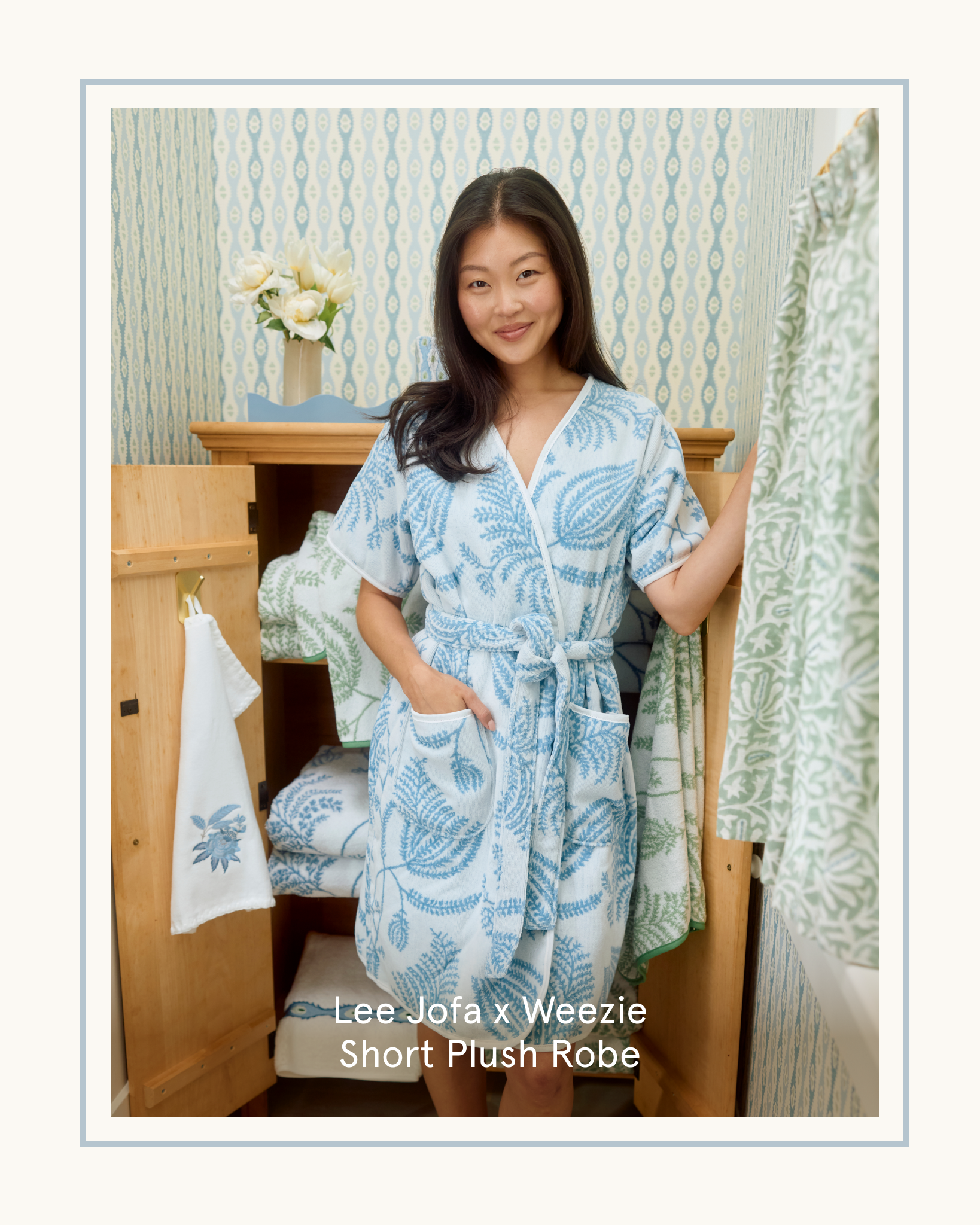 A woman in a blue and white patterned robe stands in front of an open wooden cabinet.