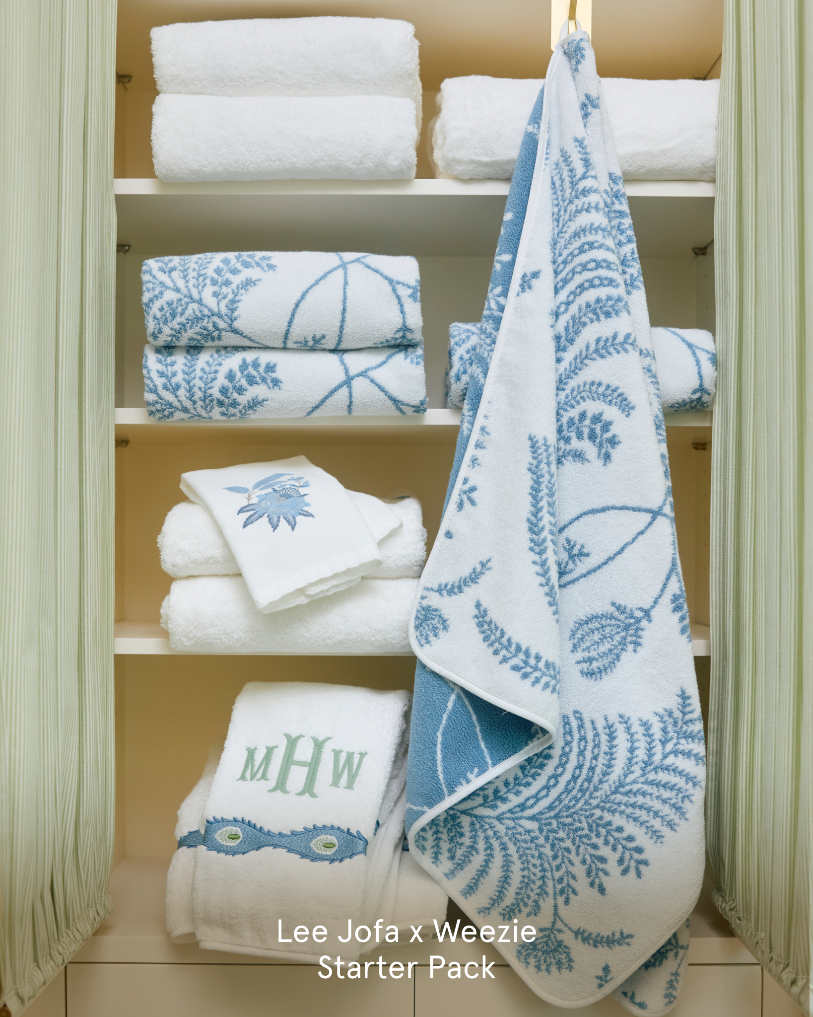 A closet with shelves of folded white towels featuring blue embroidery, patterns, and a monogram.
