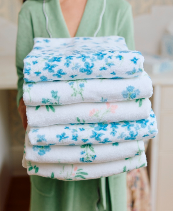 Person holding a stack of floral-patterned towels.