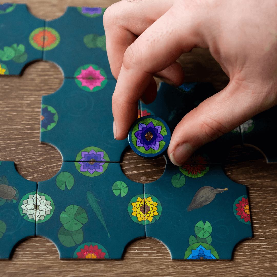 Hand placing a circular puzzle piece with floral design.