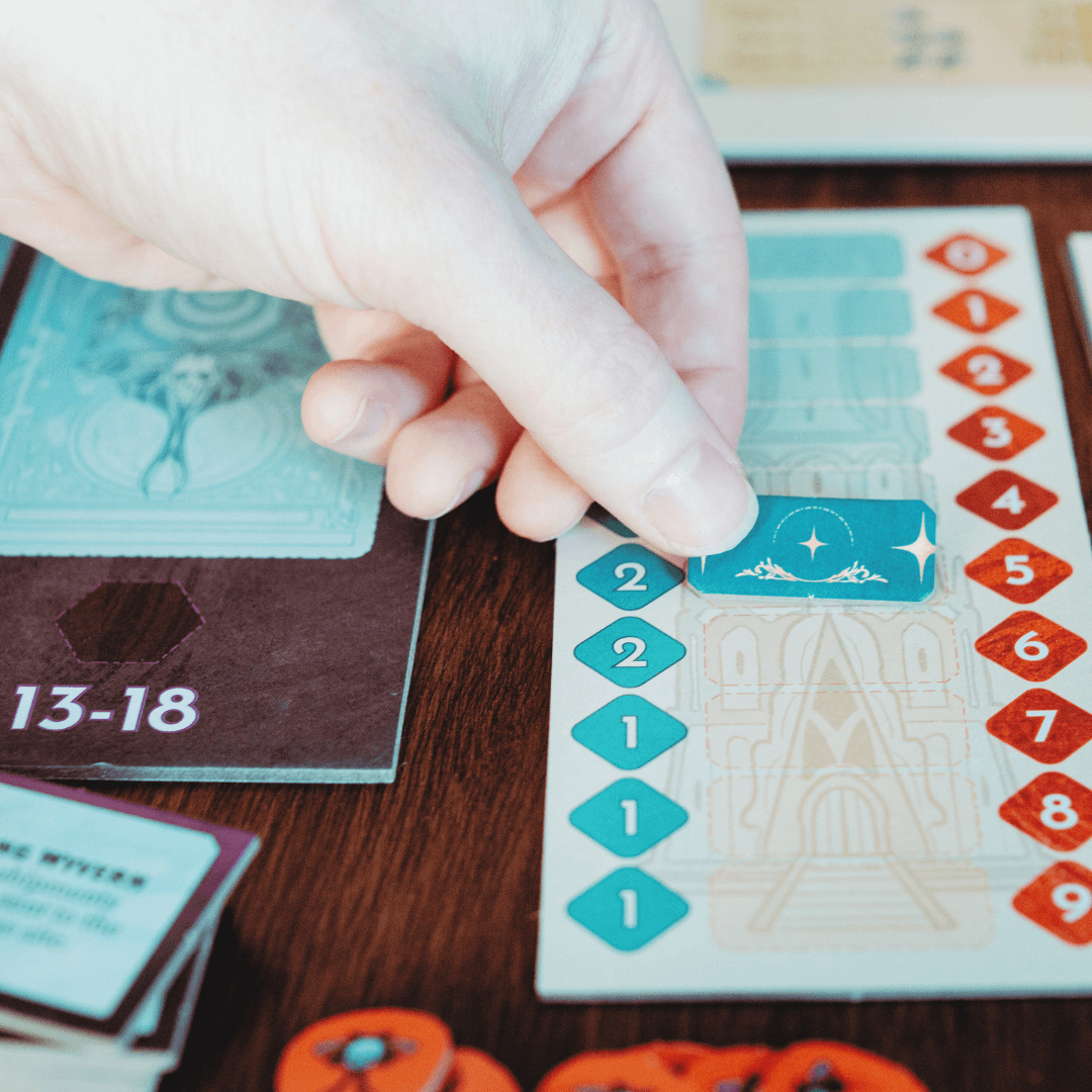 Hand moving a game piece on a board with numbers and symbols.