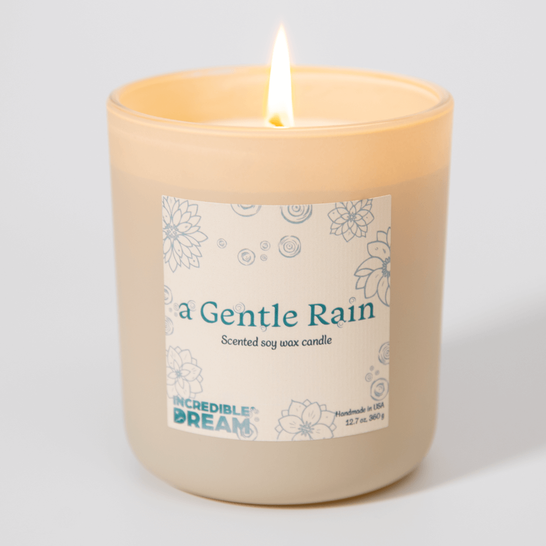 Lit candle labeled 'A Gentle Rain' with floral design.