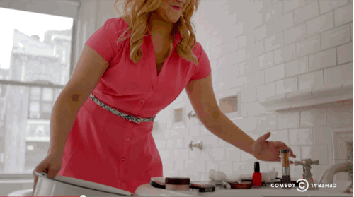 Person in pink dress turning on bathroom sink faucet.
