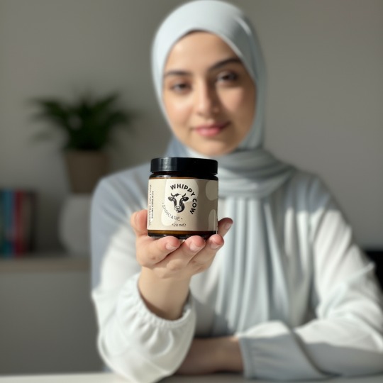 Person holding Whippy Cow skincare cream, smiling, with product on their finger.