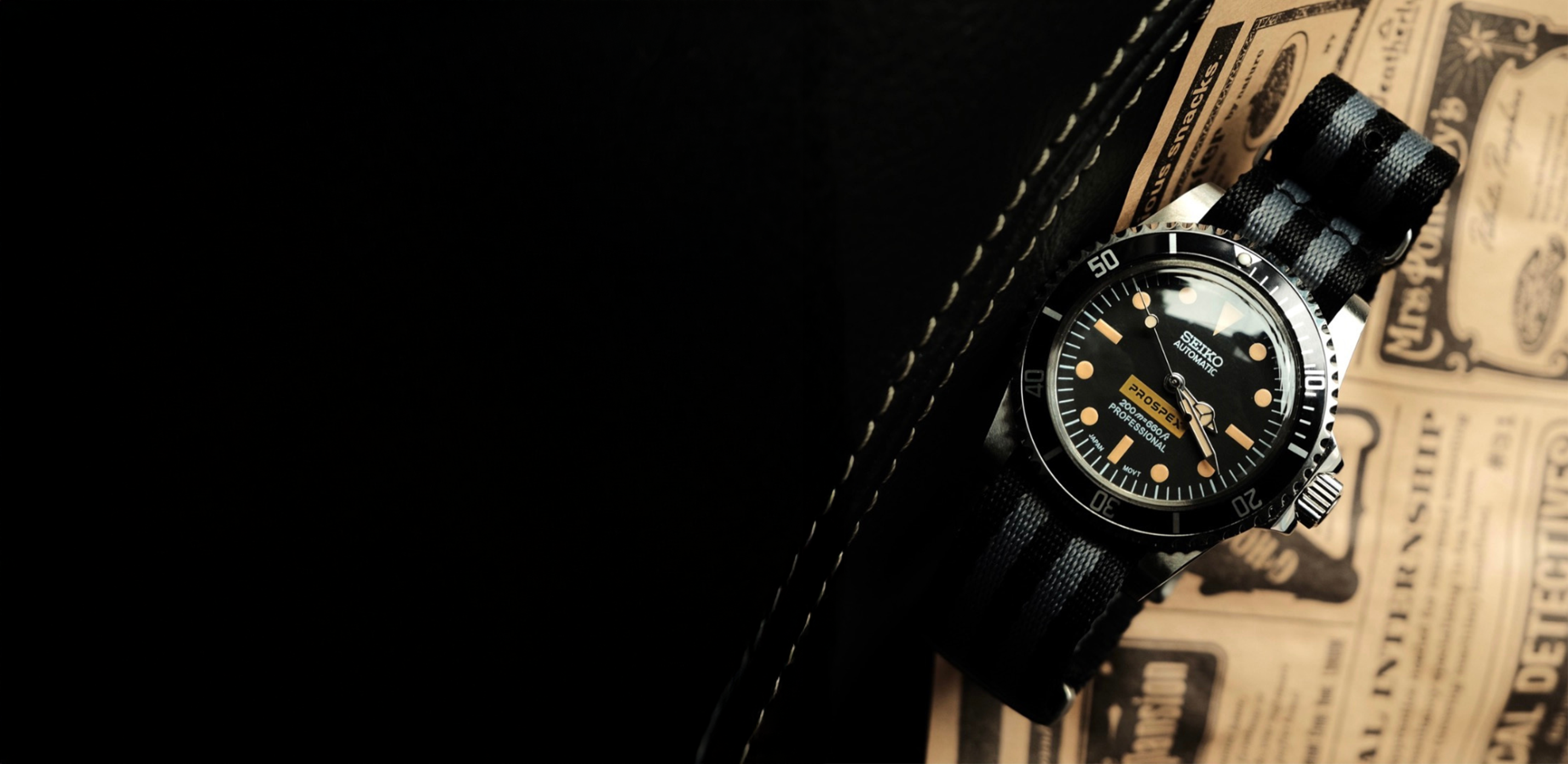 Seiko Prospex watch on black strap with vintage newspaper background.