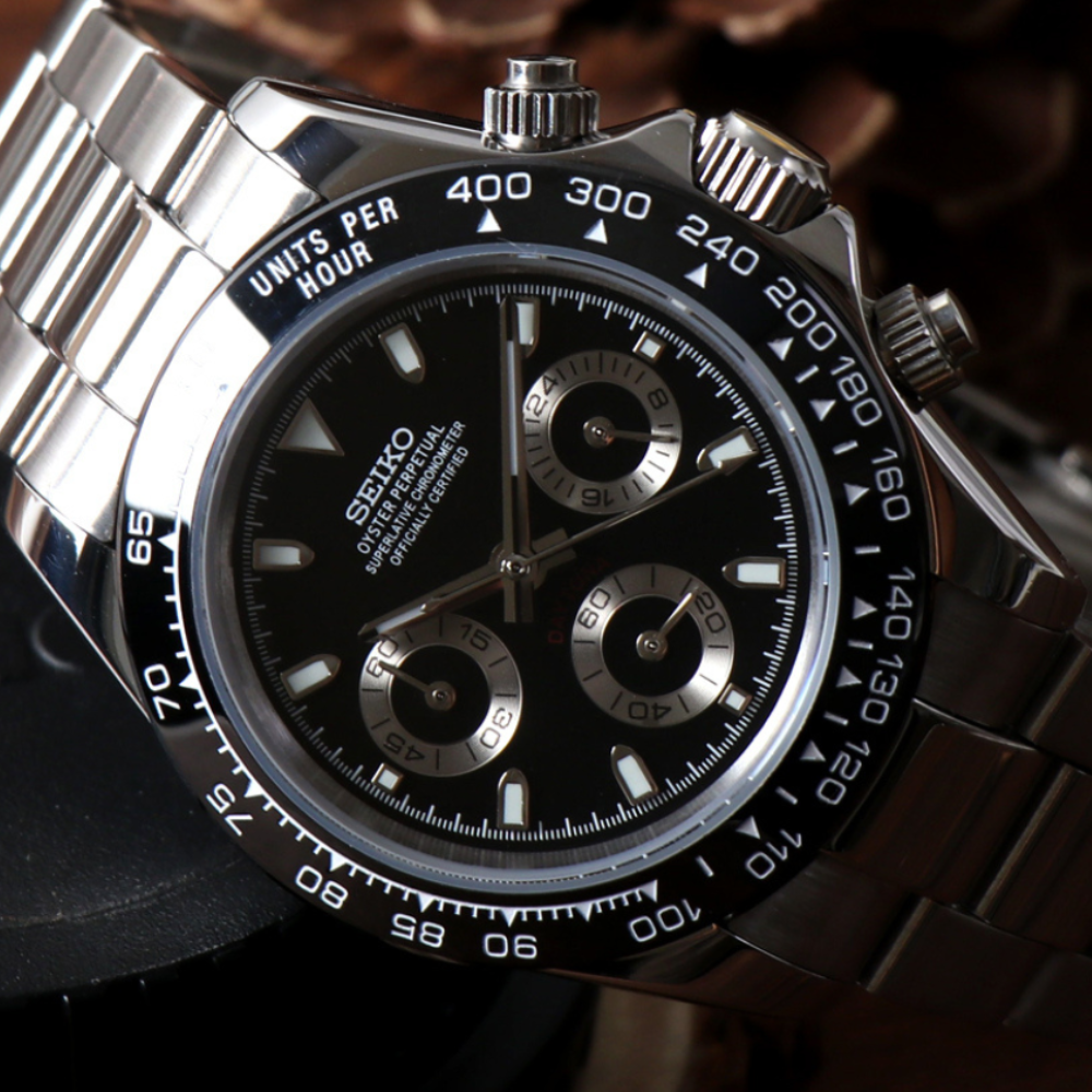 A close-up of a silver wristwatch with a black chronograph dial.