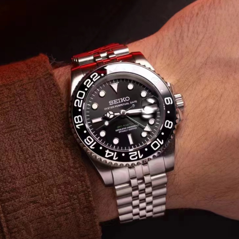 A Seiko watch with a black dial and silver bracelet on a person's wrist.