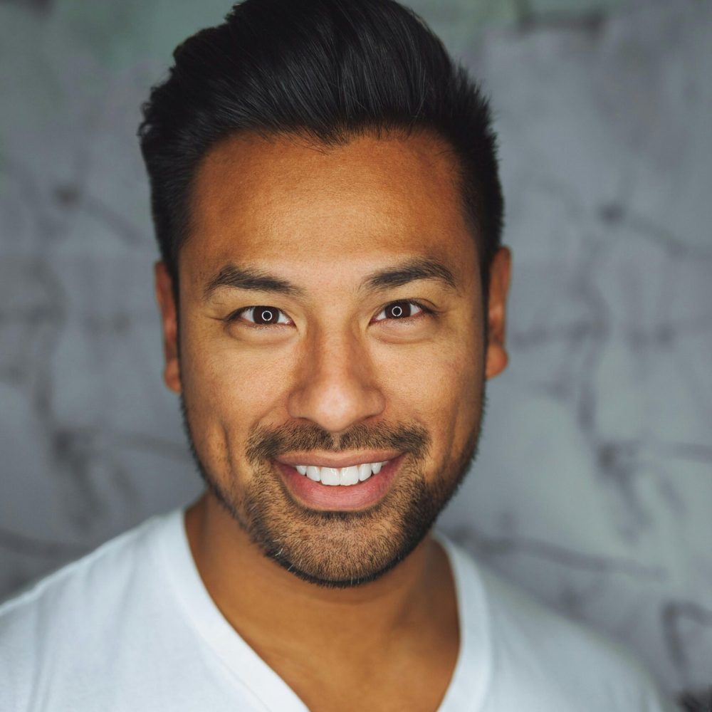 A person smiling at the camera with a blurred background.